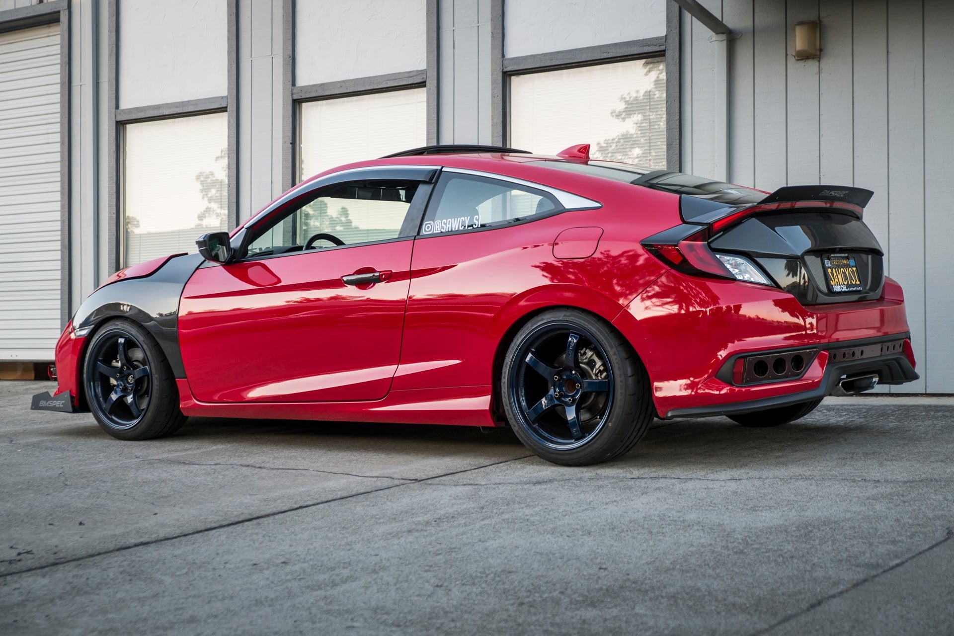 Rear three-quarter view of a red Civic non-Si Coupe with spoiler extension