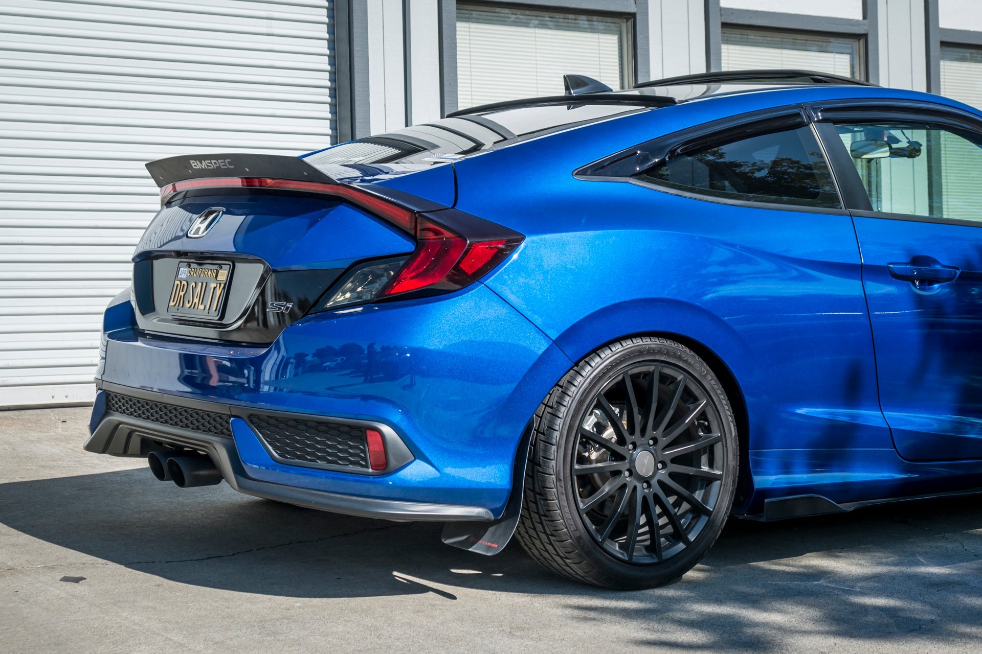 Rear three-quarter view of a blue Civic non-Si Coupe with spoiler extension