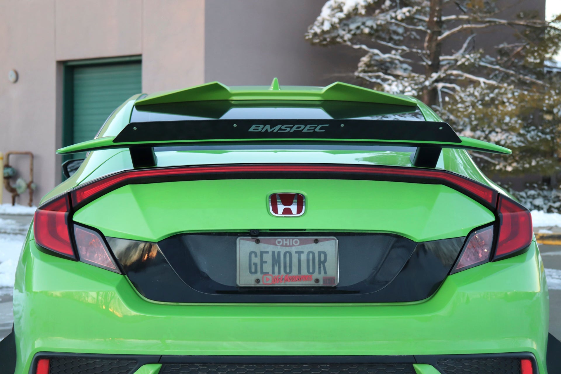 Rear view of a green Honda Civic Si Coupe with Epsilon+ spoiler extension mounted on the OEM wing