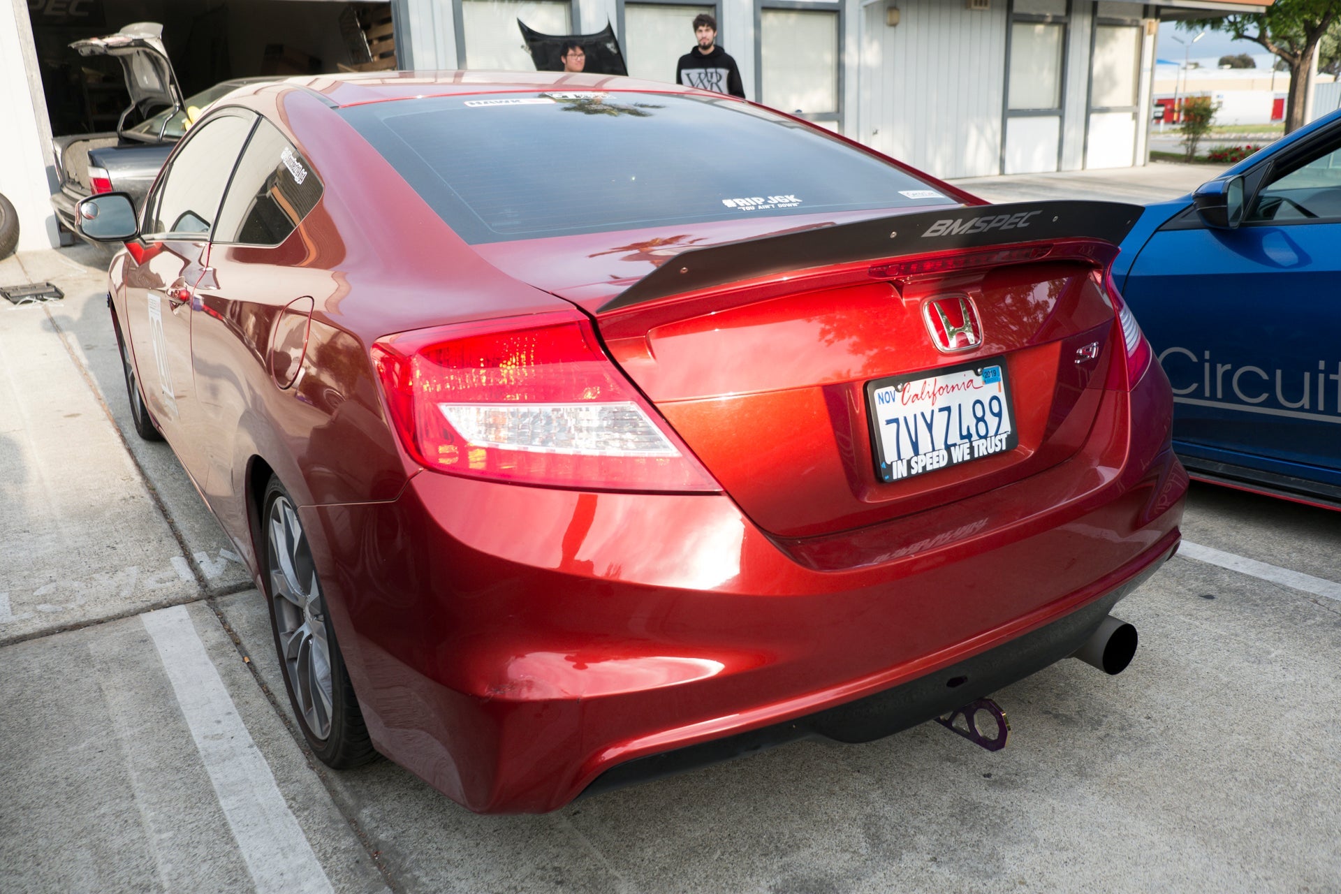 Rear three-quarter view of a red Civic Si Coupe Zenki with spoiler extension parked outdoors