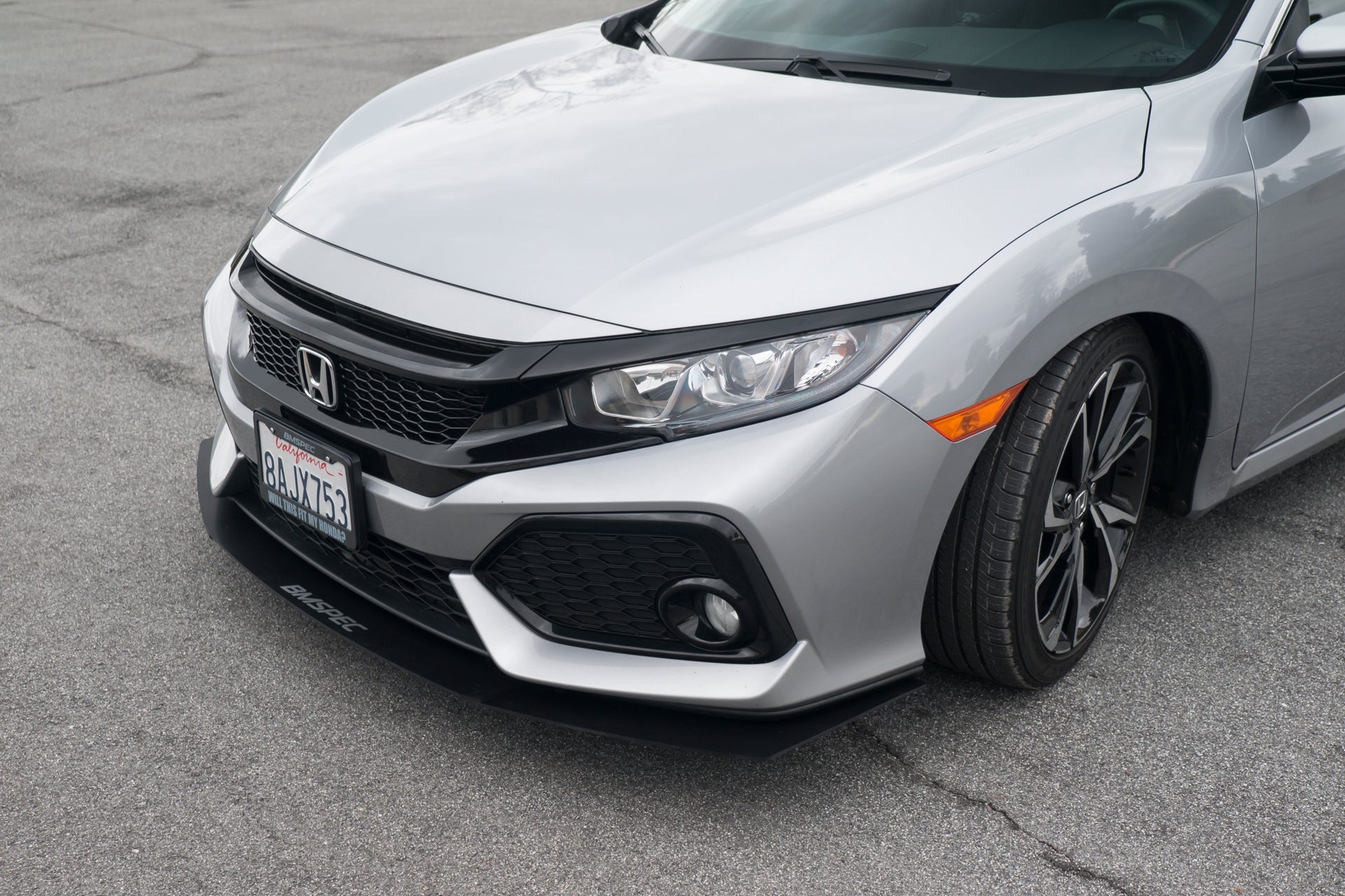 Close-up front view of the front lip mounted on a silver Civic Si Hatchback-style front bumper