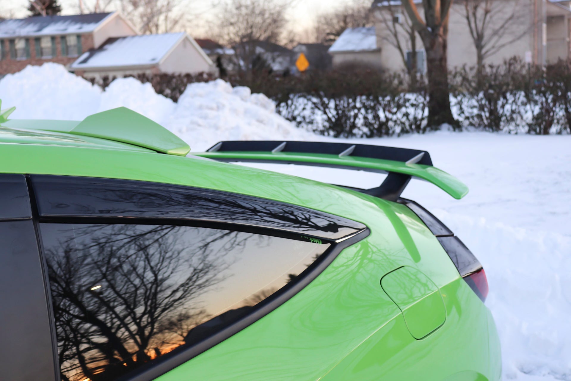 Close-up of the spoiler extension mounted on a green Civic Si Coupe, rear window angle