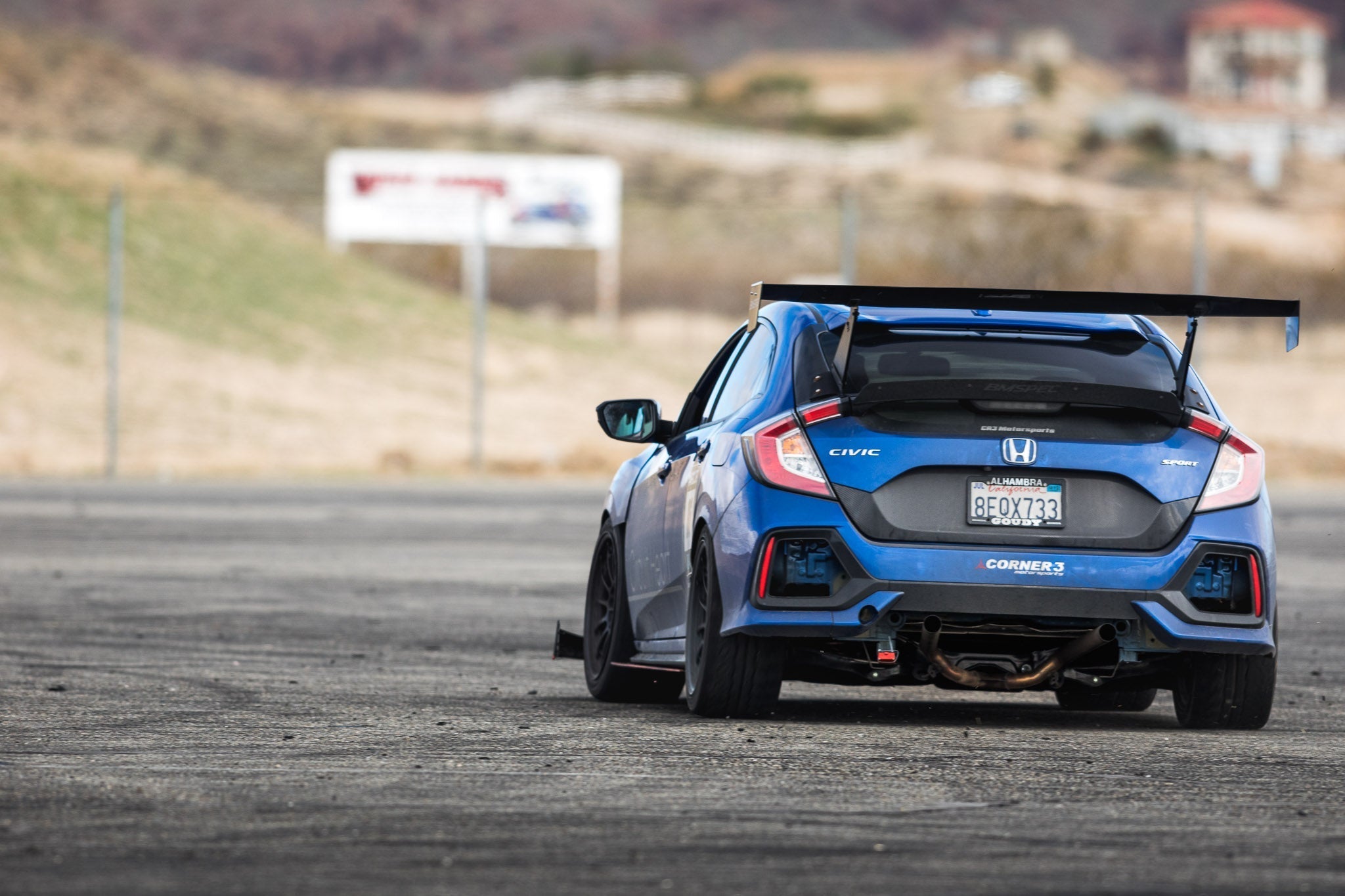 Blue Civic Type R FK8 with GT wing on a road course near corner 2