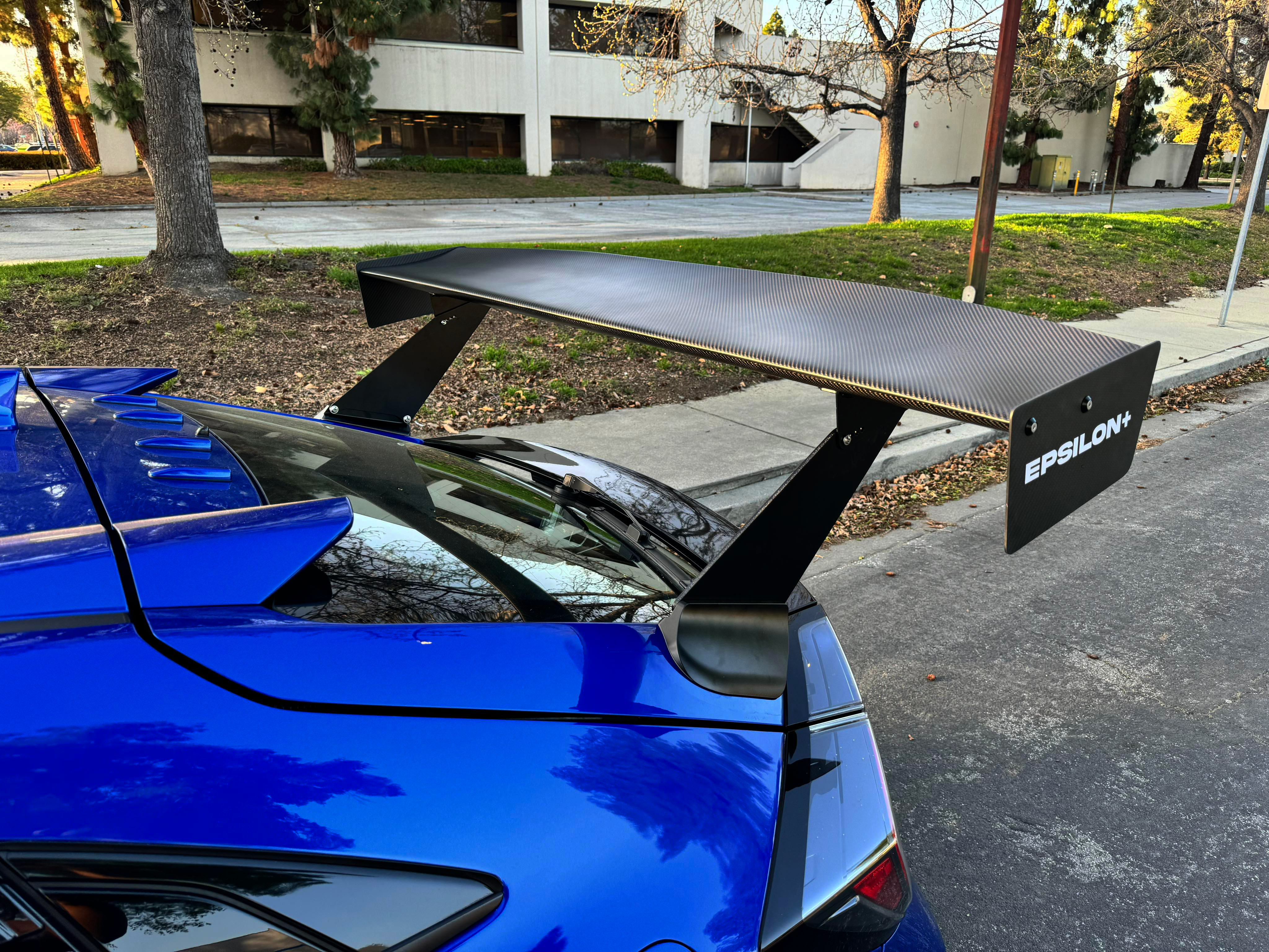 Top-down view of the carbon fiber weave on the Epsilon+ GT wing blade with endplate branding
