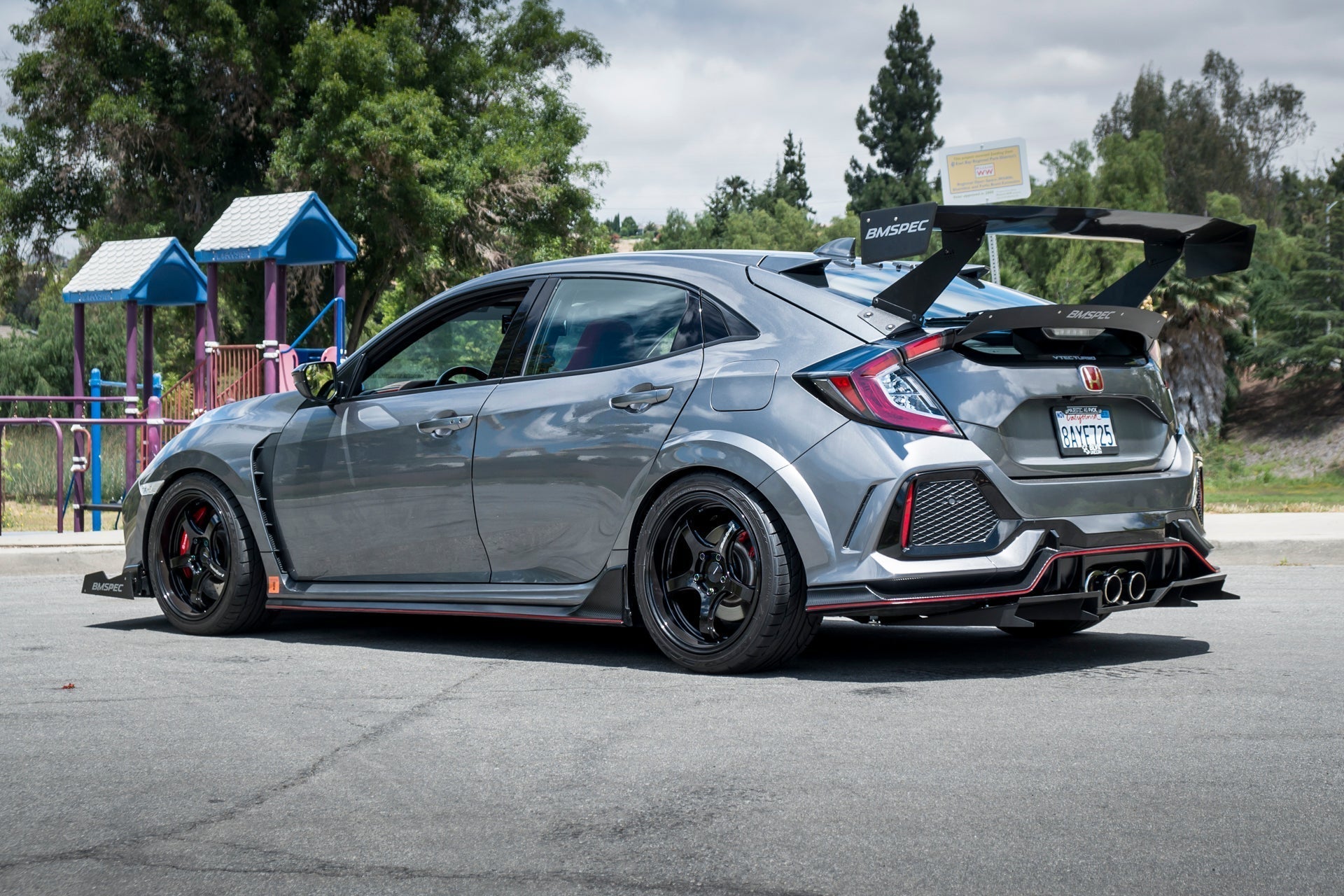 Gray Civic Type R side-rear view with GT wing parked near a playground