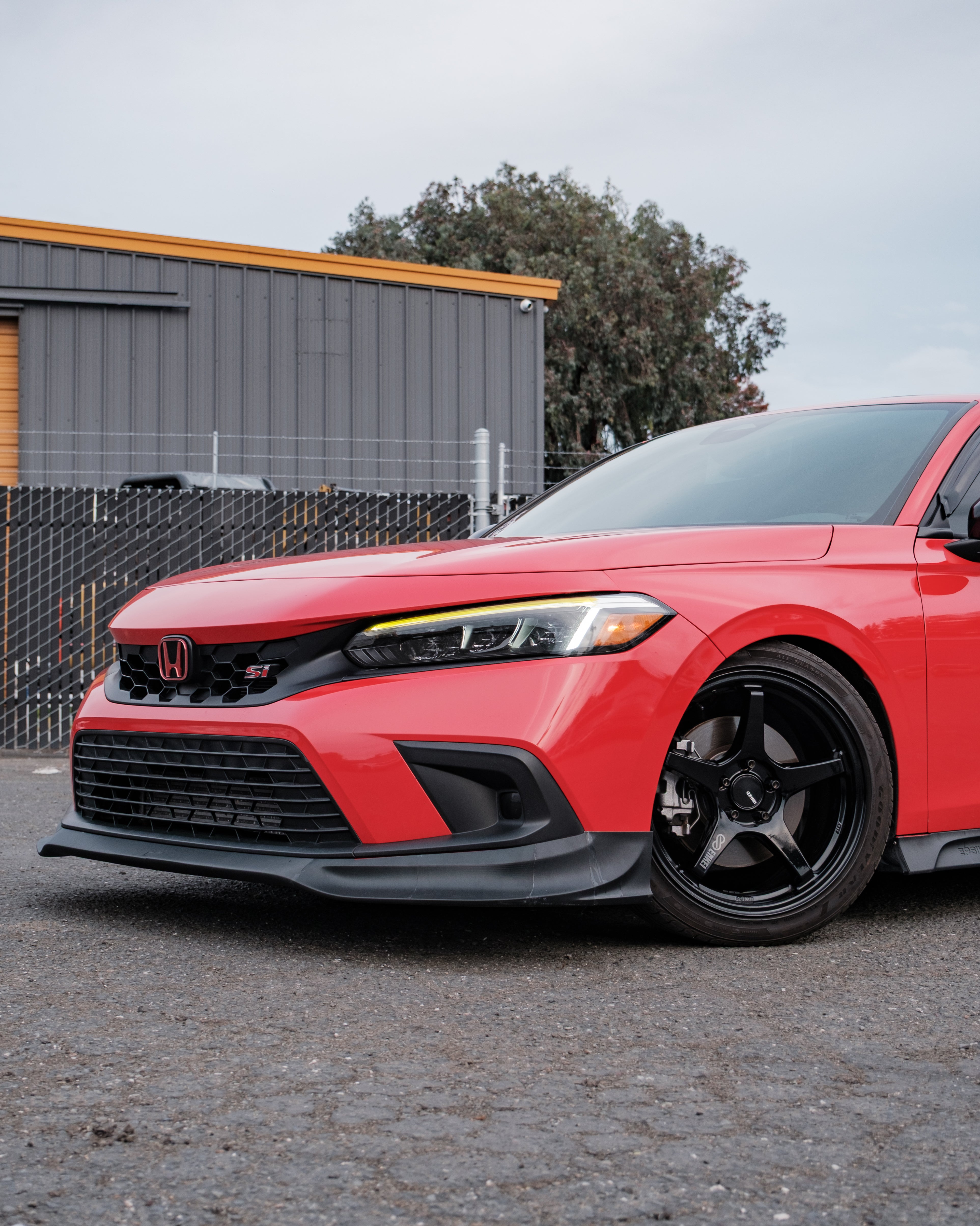 Close front three-quarter view of the Epsilon+ front lip on a red Honda Civic