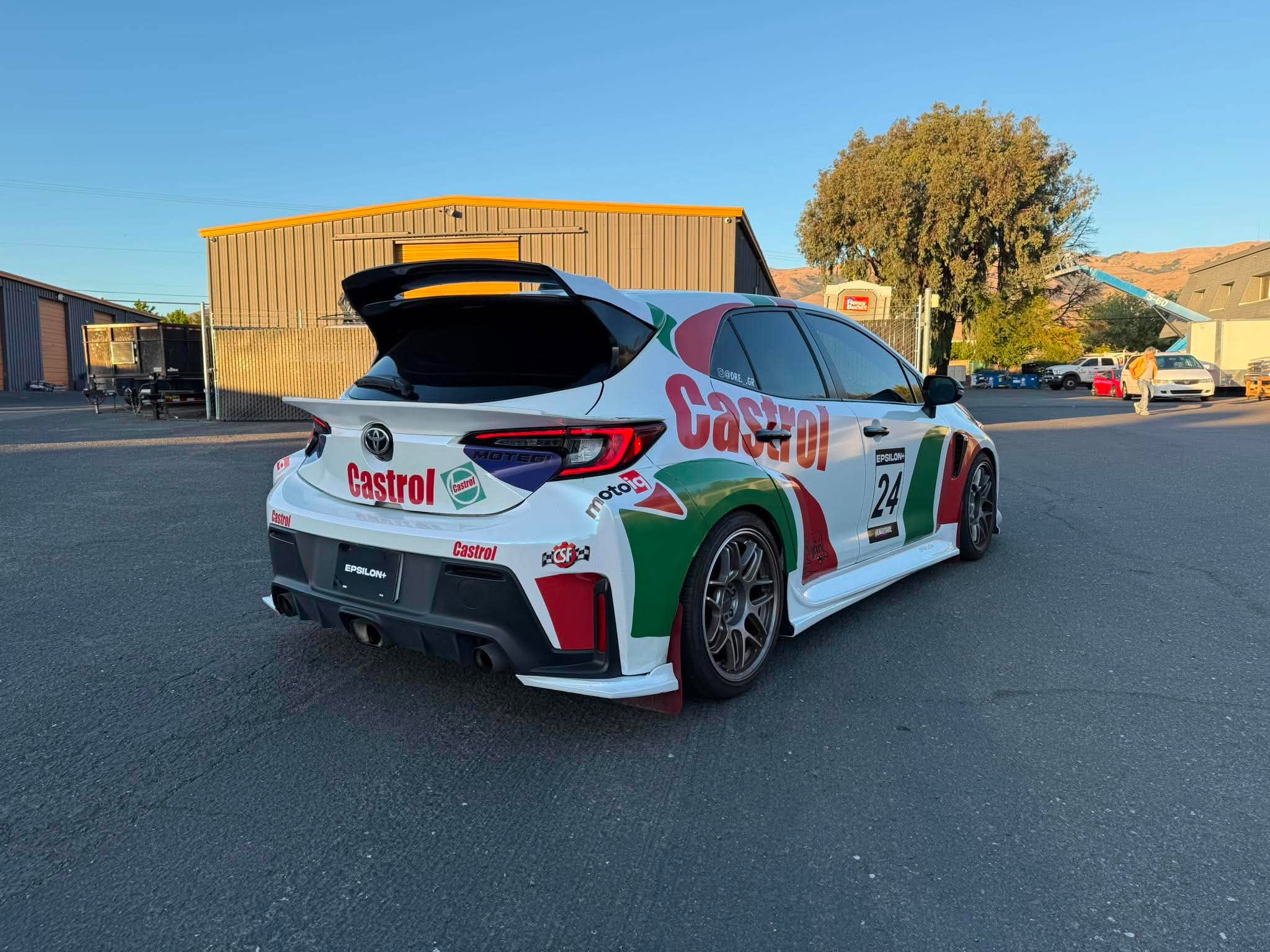 Castrol-liveried Corolla Hatchback with mid wing parked beside a warehouse