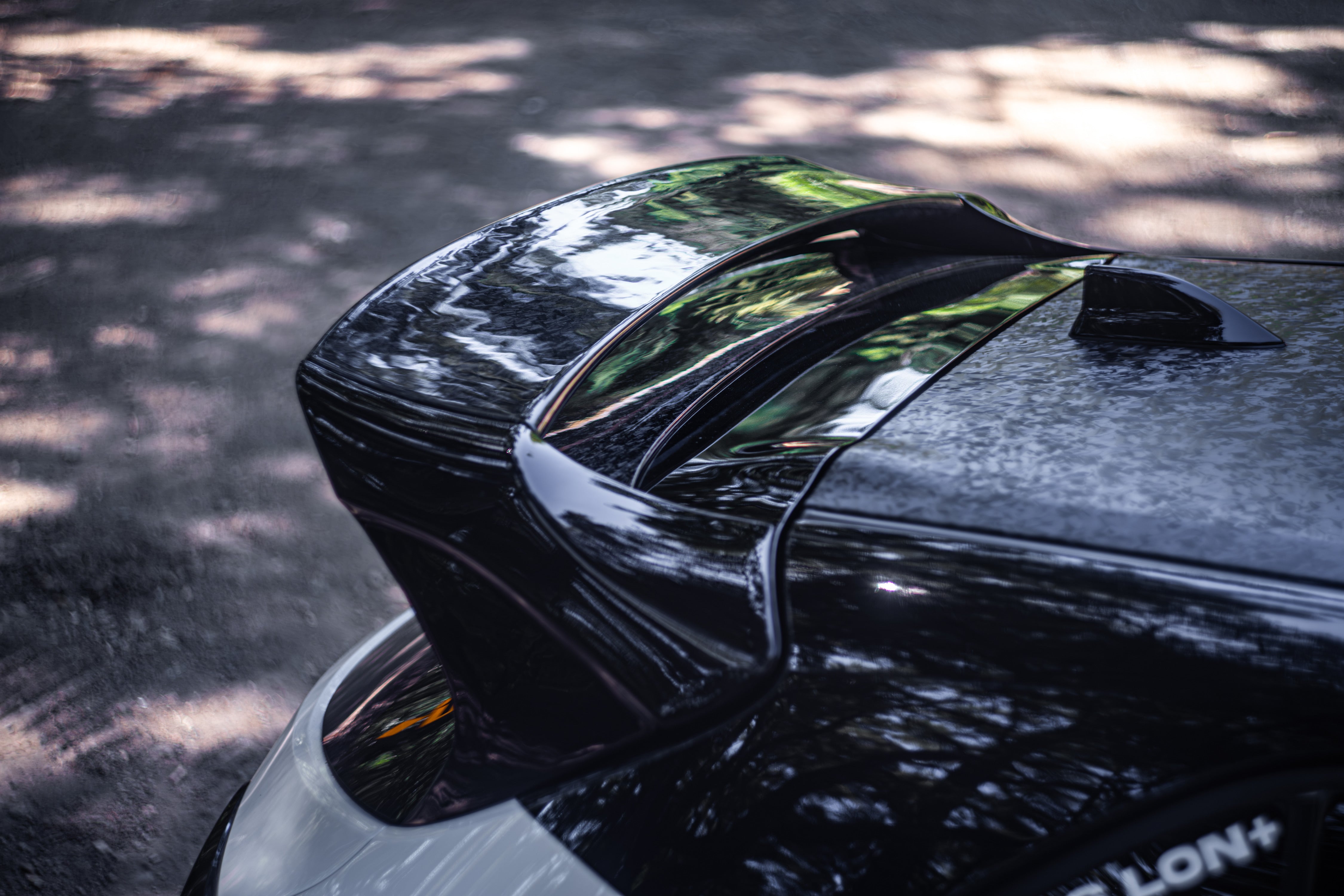 Close-up of the carbon fiber WRC Wing V3 blade on a black Corolla Hatchback roofline