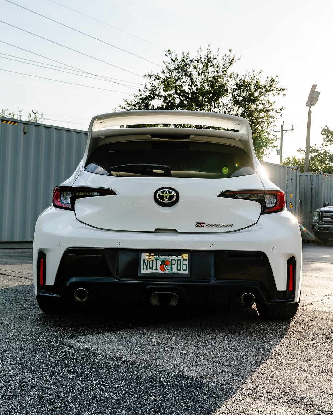 Rear view of a white Corolla Hatchback with WRC Wing V3, parked at dusk