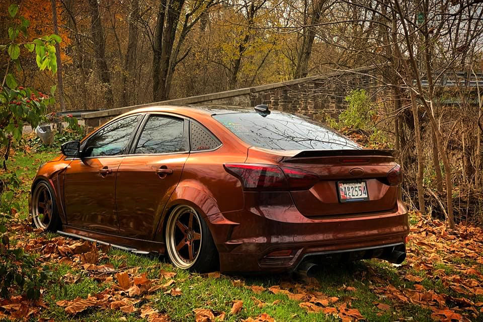 Rear three-quarter view of a bronze wrapped Ford Focus Sedan with spoiler extension