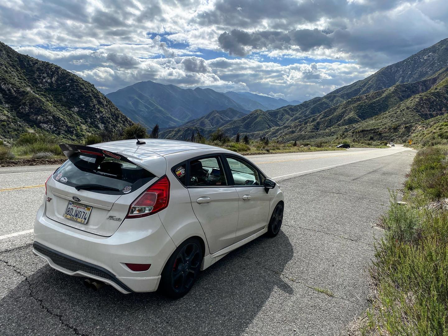 White Fiesta ST with spoiler extension on a canyon road with mountain views