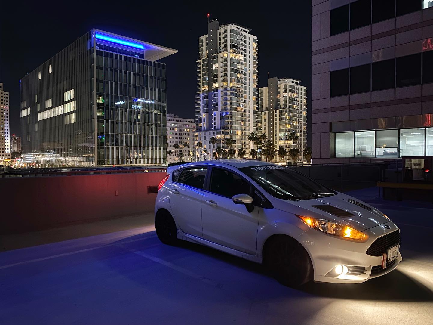 White Fiesta ST with spoiler extension parked in a city at night