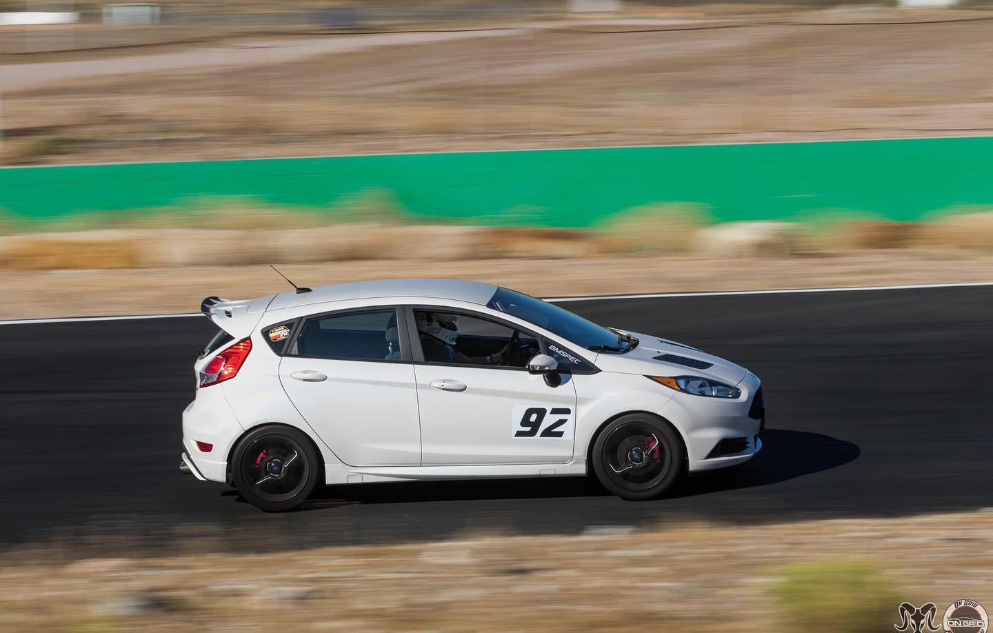 White Ford Fiesta ST motorsport car with spoiler extension panning shot on a track