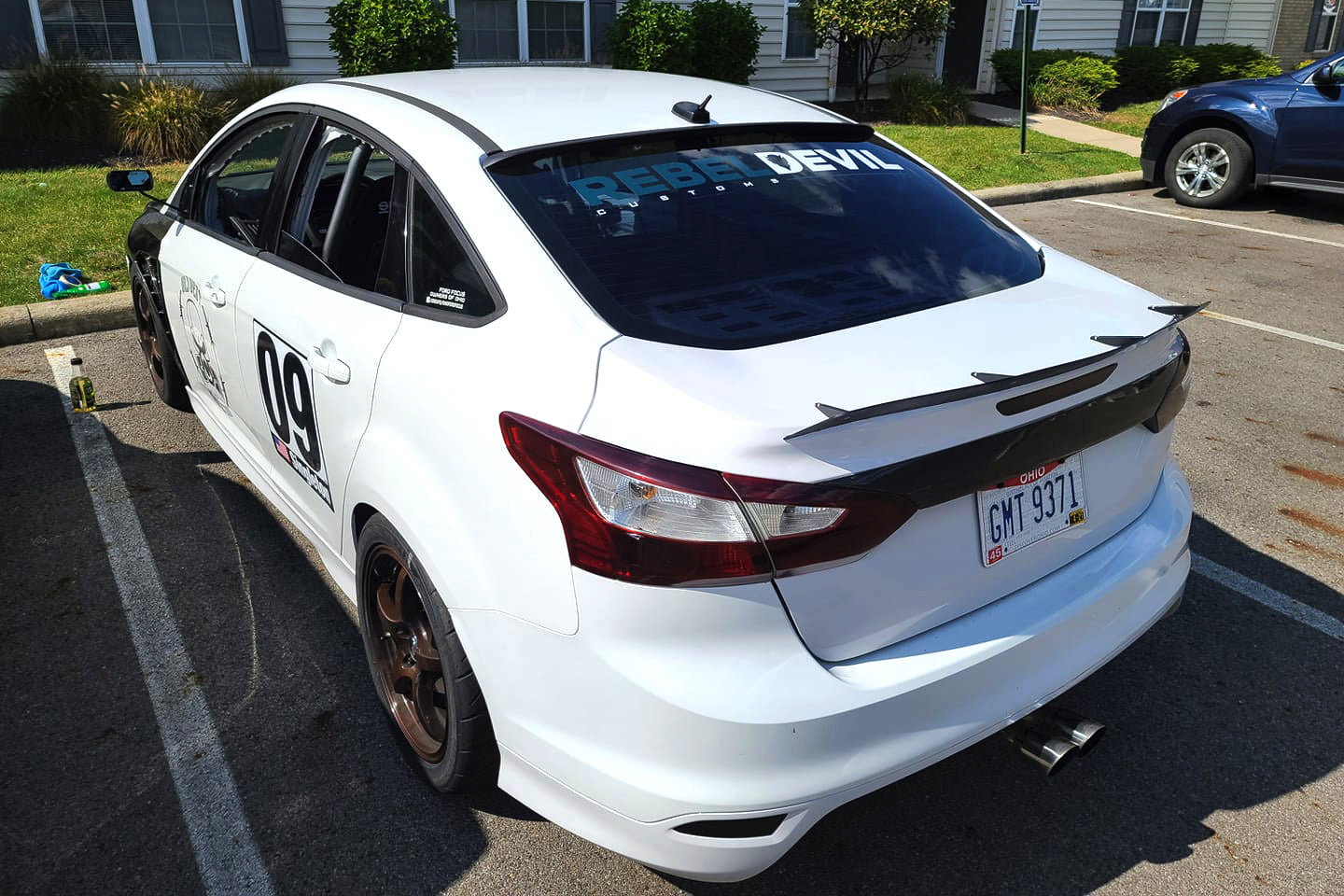 Rear view of a white Ford Focus Sedan motorsport car with spoiler extension