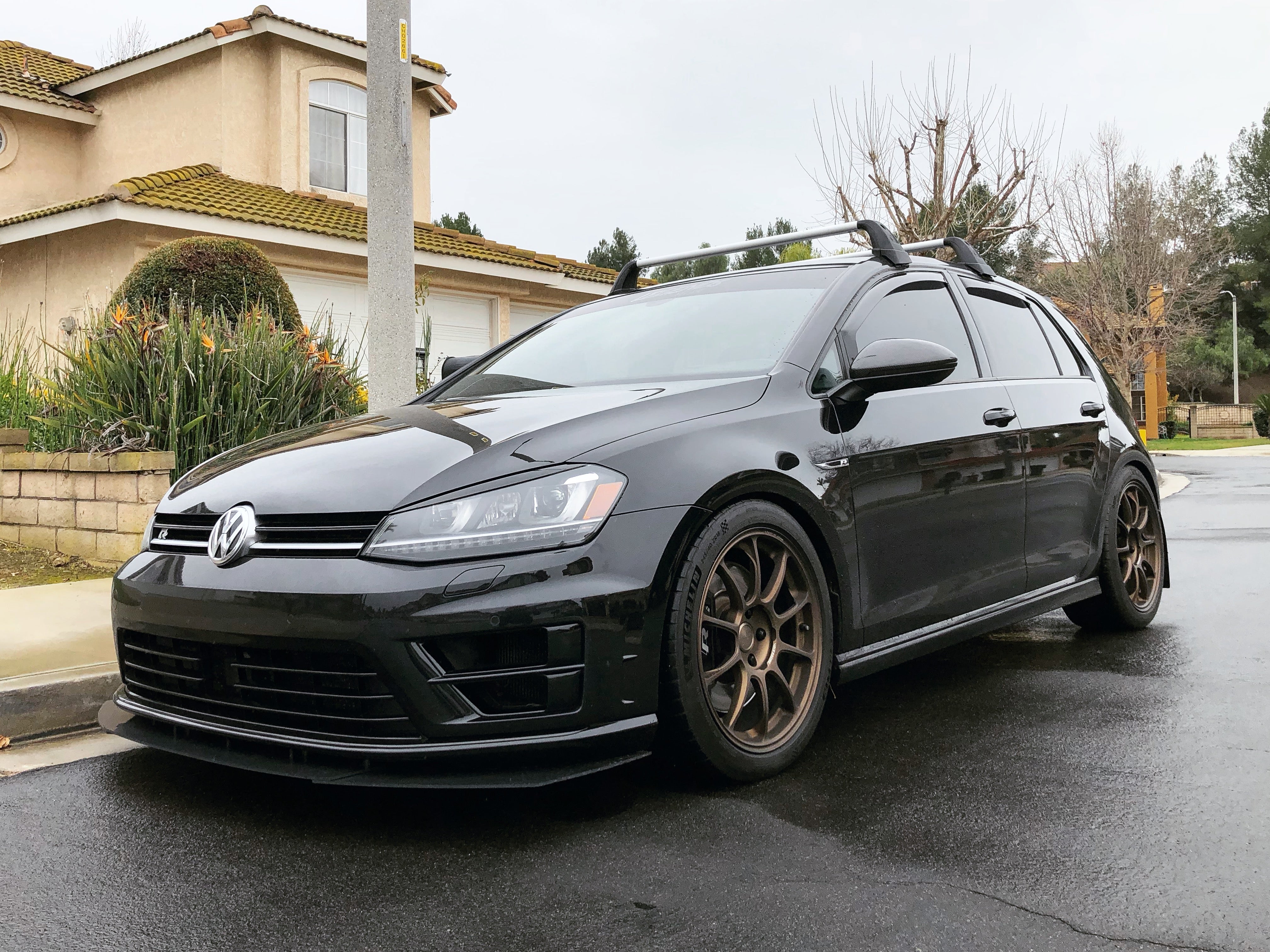 Front three-quarter view of a black Golf R with front lip and bronze wheels