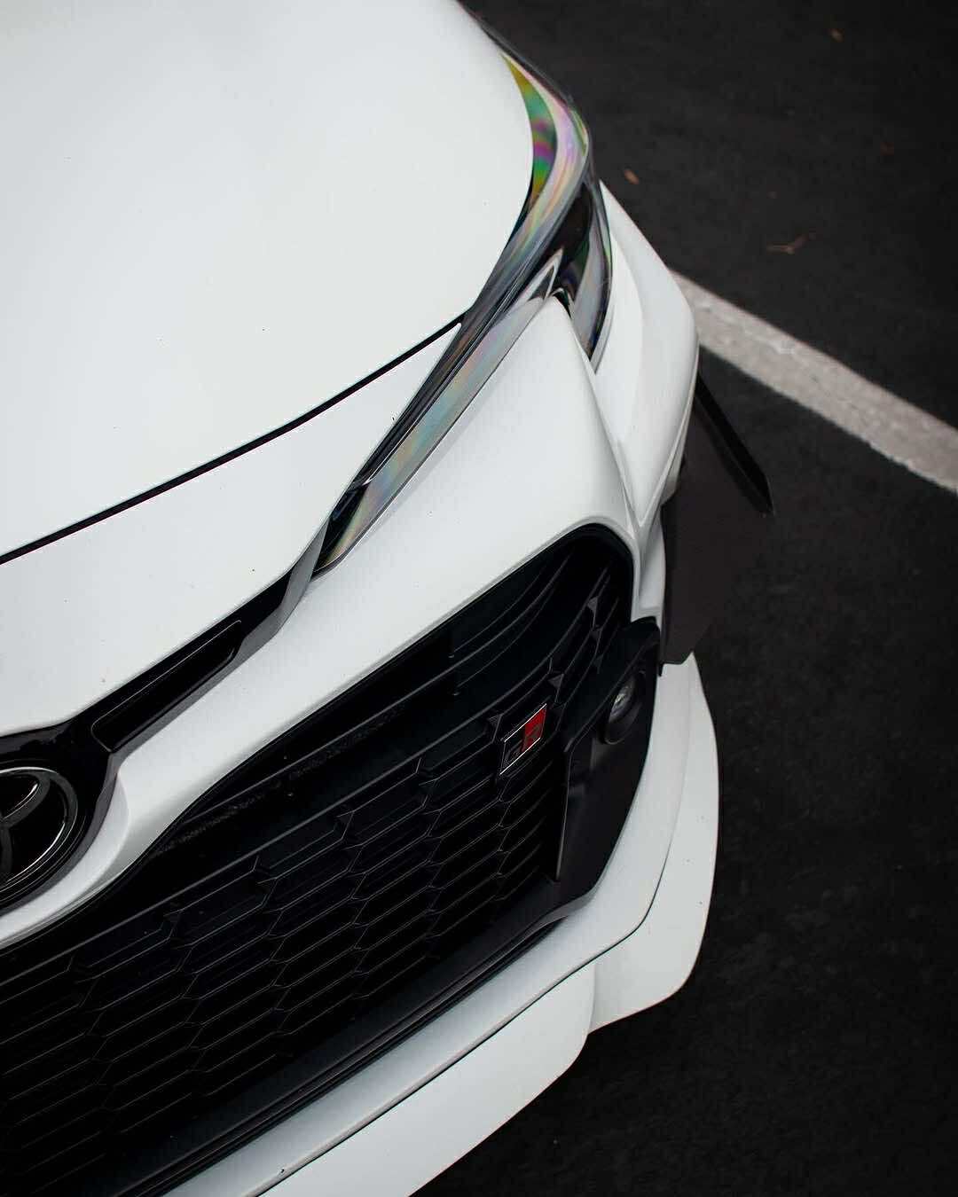 Close-up of a carbon fiber canard mounted on a white GR Corolla bumper