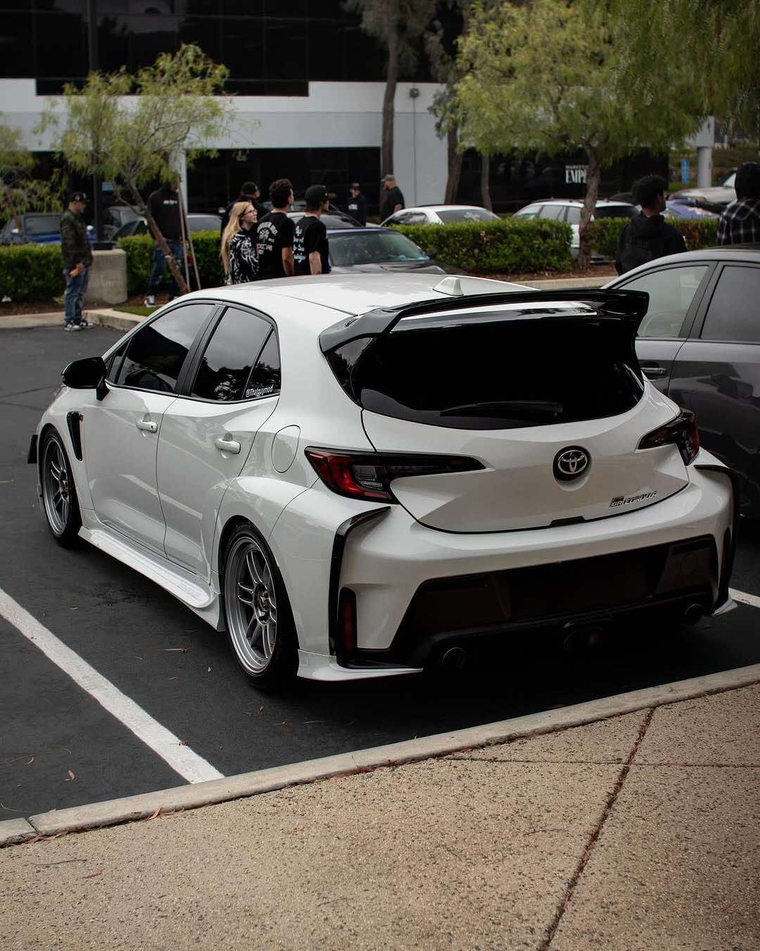 Rear three-quarter view of a green GR Corolla with WRC Wing V3 on a road at sunset