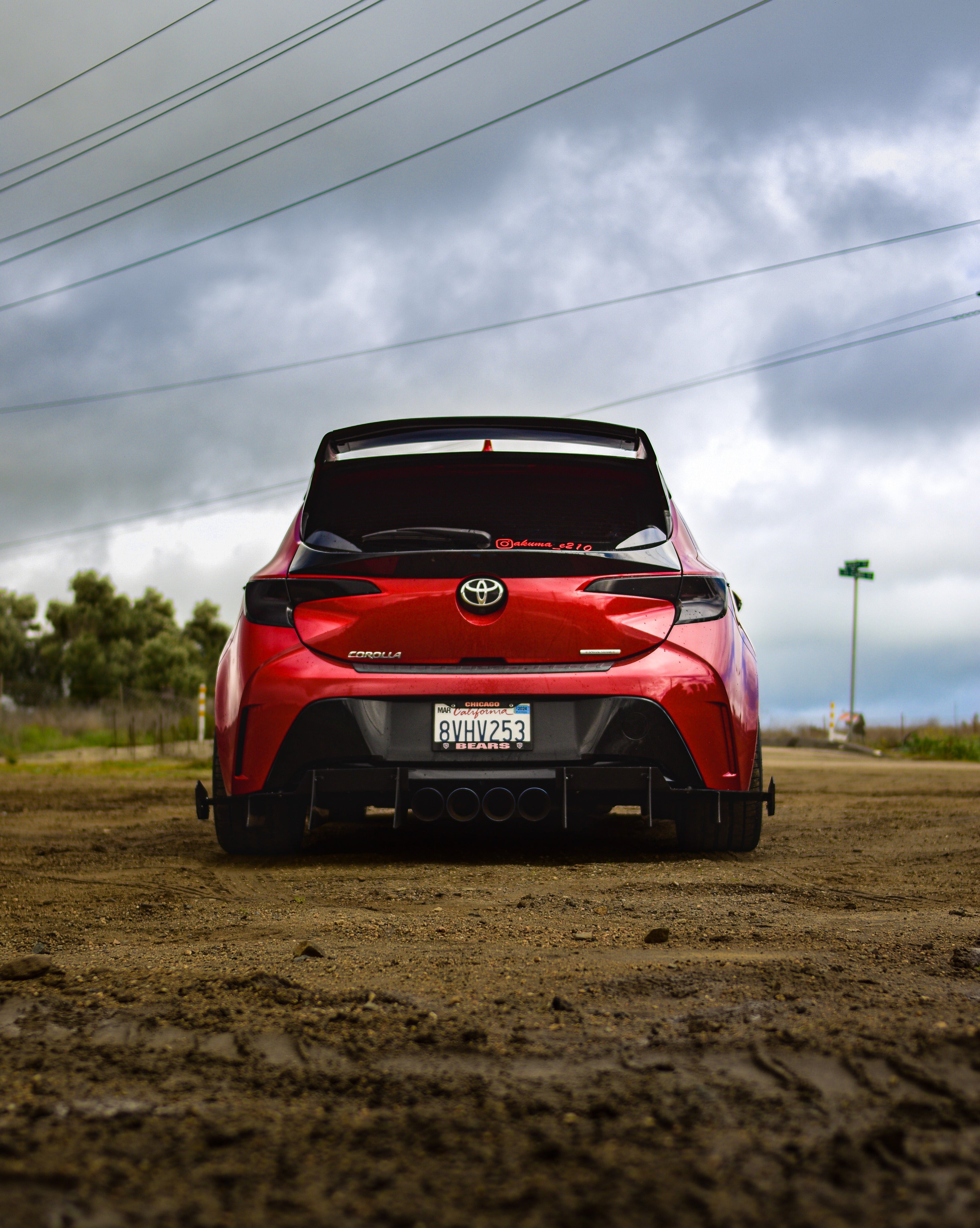Rear view of a red GR Corolla with WRC Wing V3 in an open field