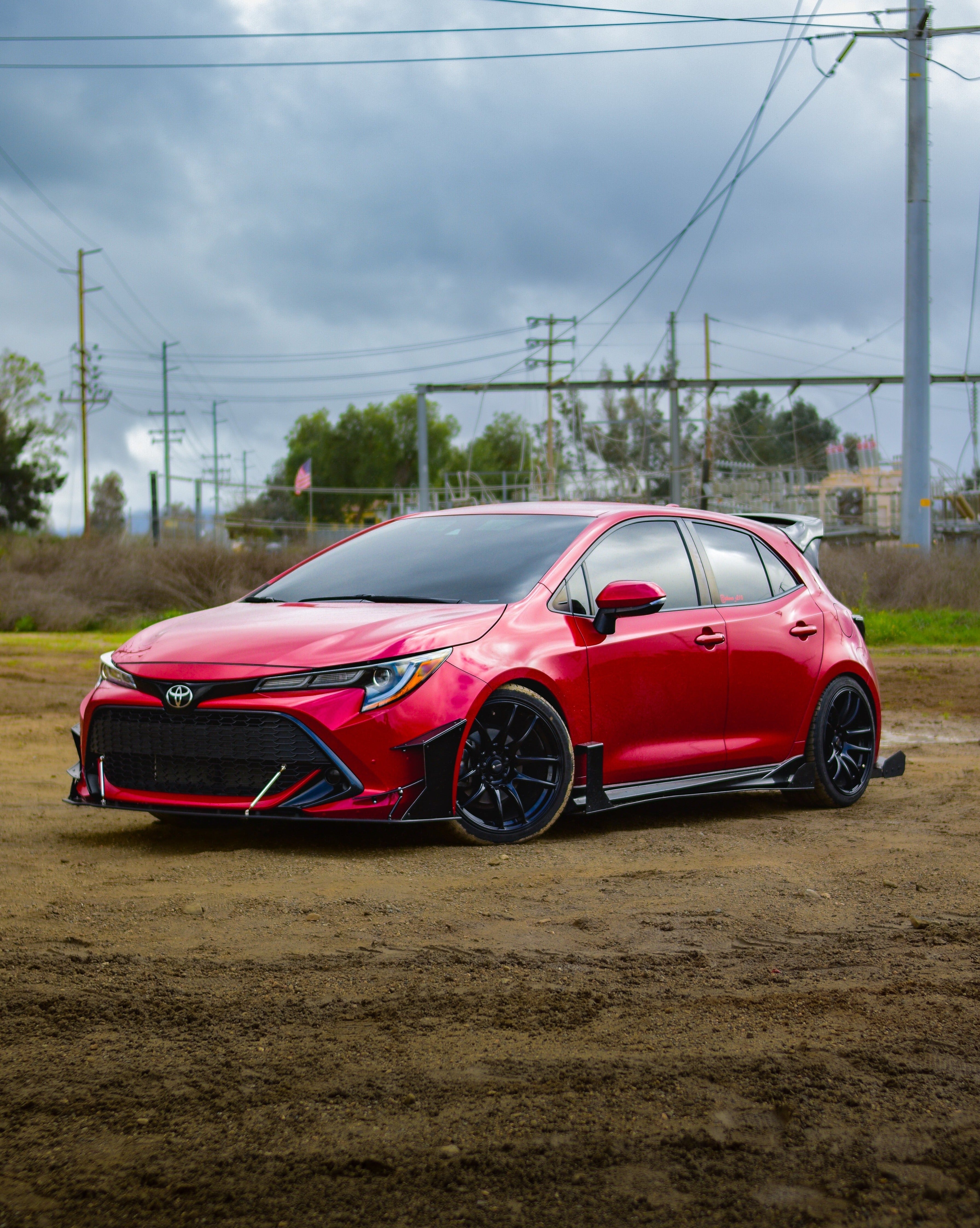 Front three-quarter view of a red GR Corolla with WRC Wing V3 on a residential street