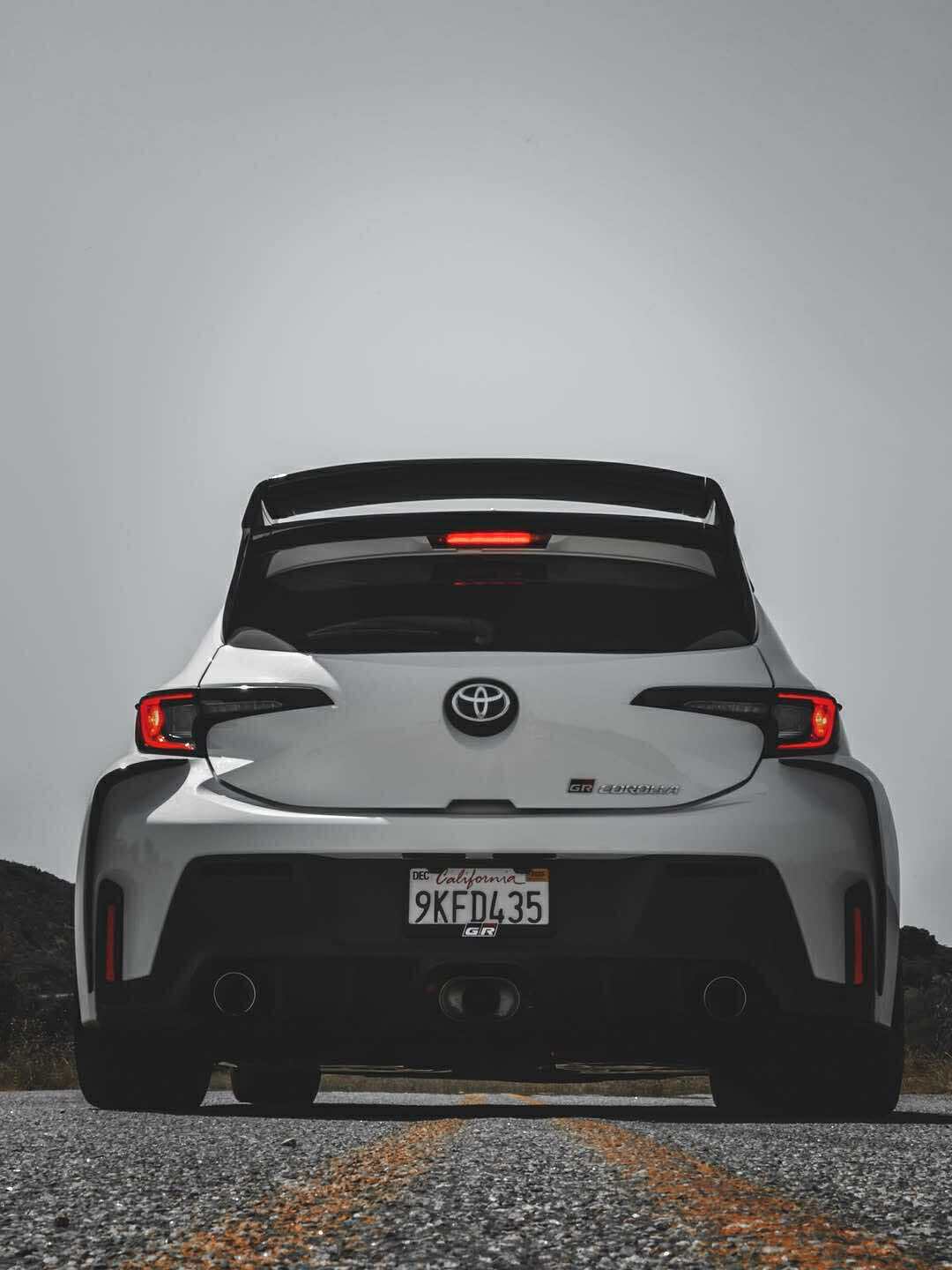 Rear three-quarter view of a white GR Corolla with WRC Wing V3 in a parking lot