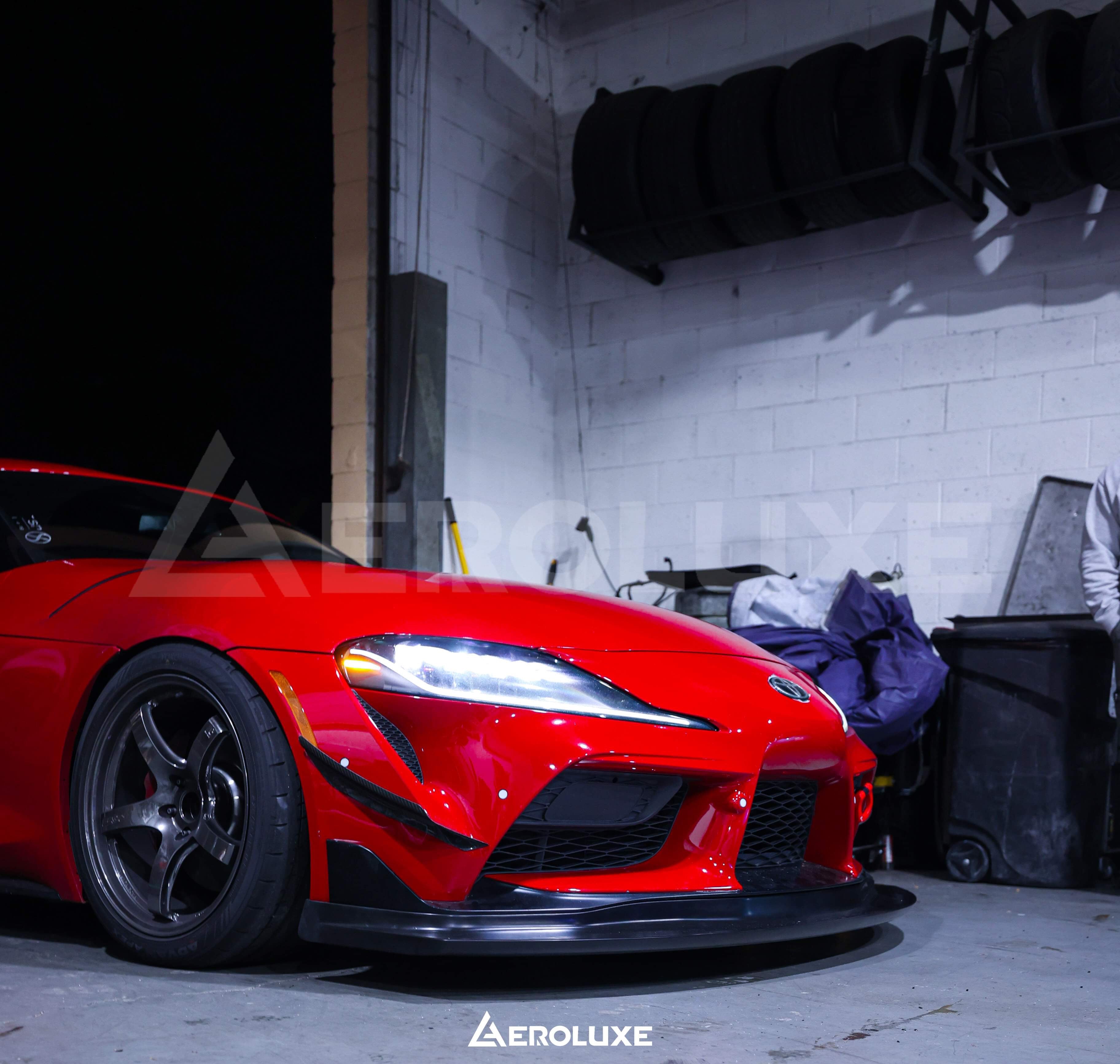 Red Toyota GR Supra with GT4-spec front lip parked in a garage