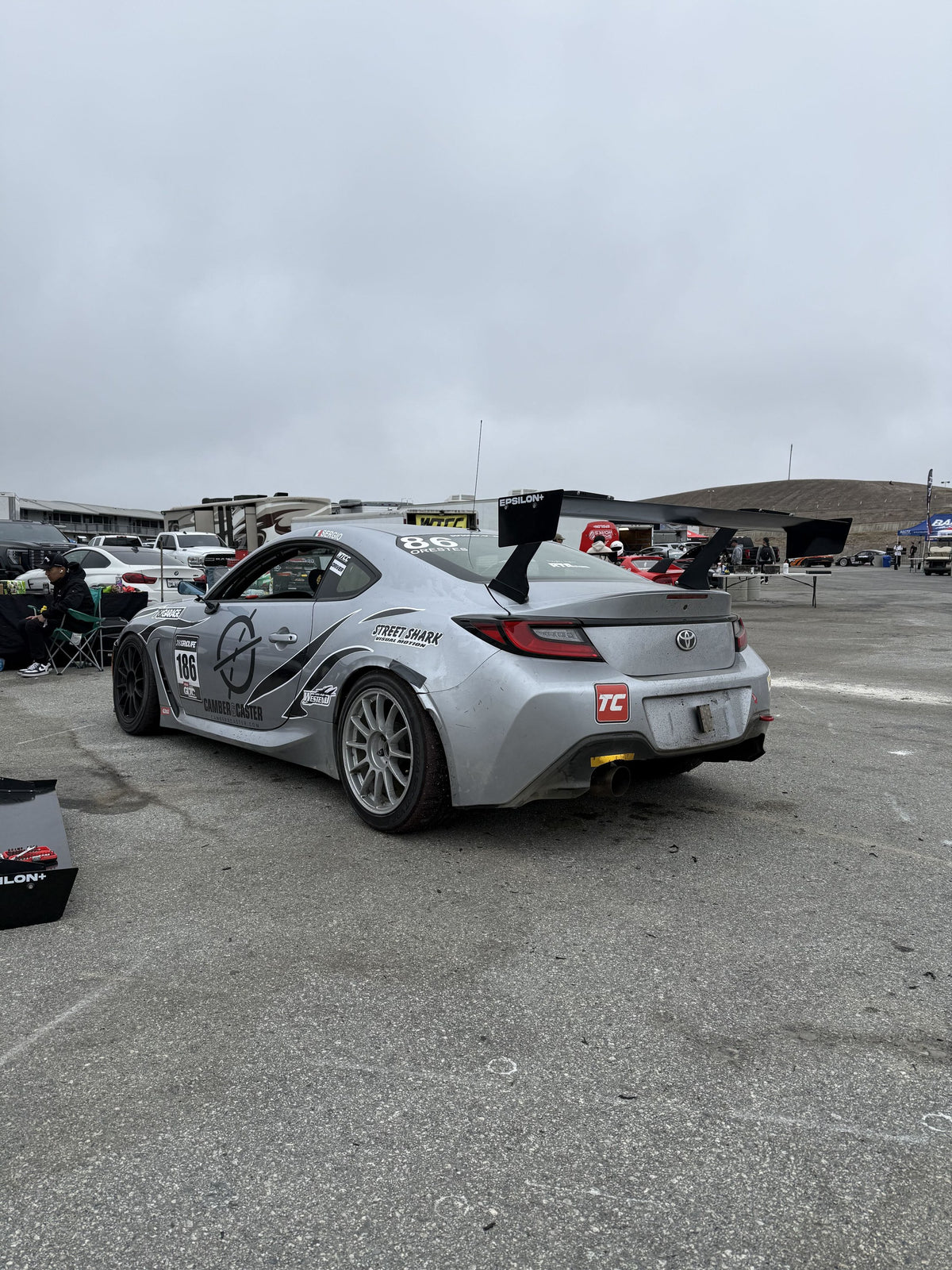 Toyota GR86 (ZN8) TC race car fitted with the Epsilon+ TC Wing, rear three-quarter view in the paddock