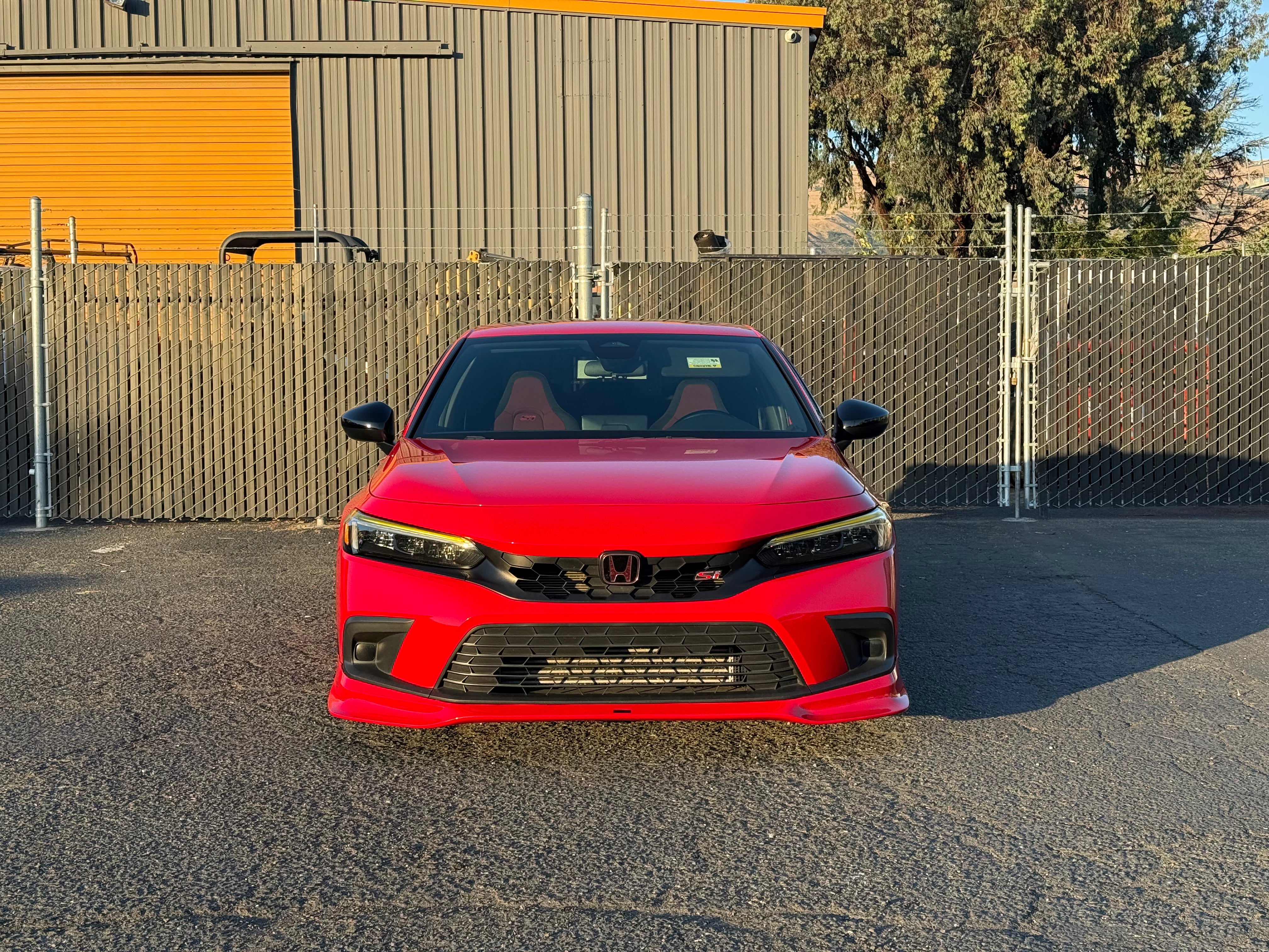 Red Honda Civic with the Epsilon+ front lip parked by a warehouse