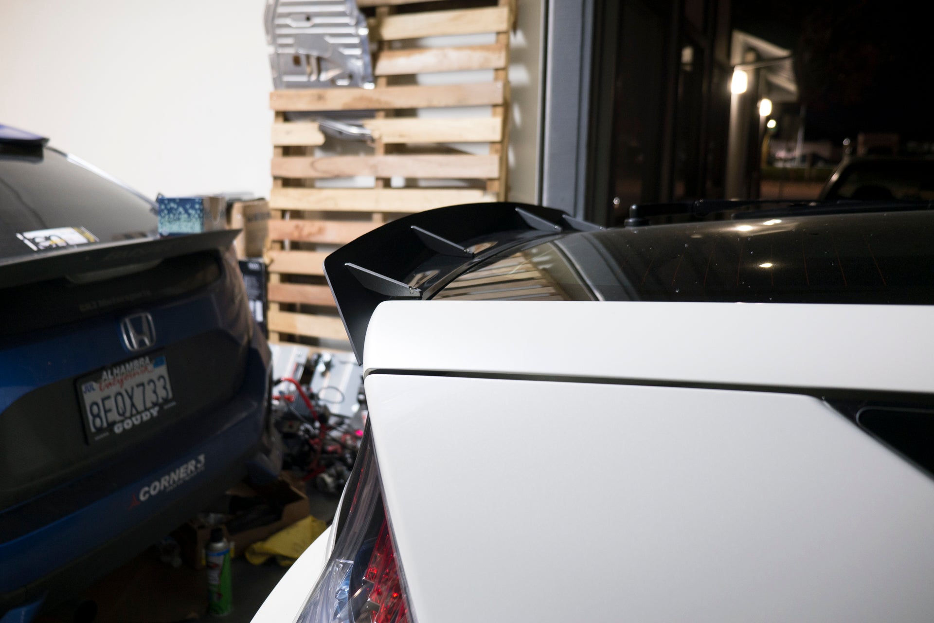 Close-up of the spoiler extension on a white Honda CR-Z hatch in a garage