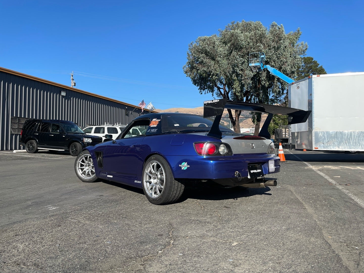 Rear three-quarter view of a blue Honda S2000 with GT wing in a parking lot