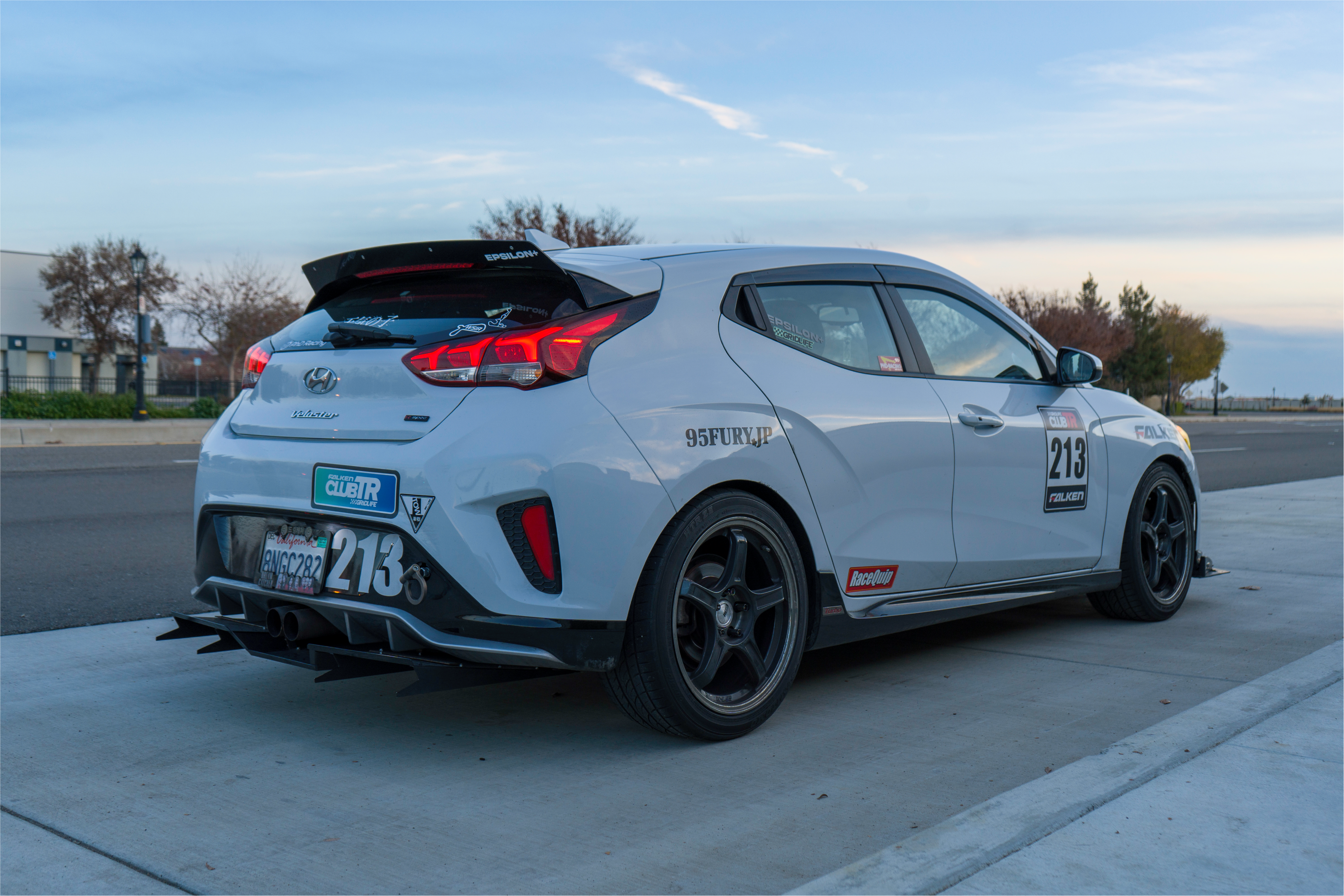 Rear three-quarter view of a white Veloster R motorsport car with spoiler extension