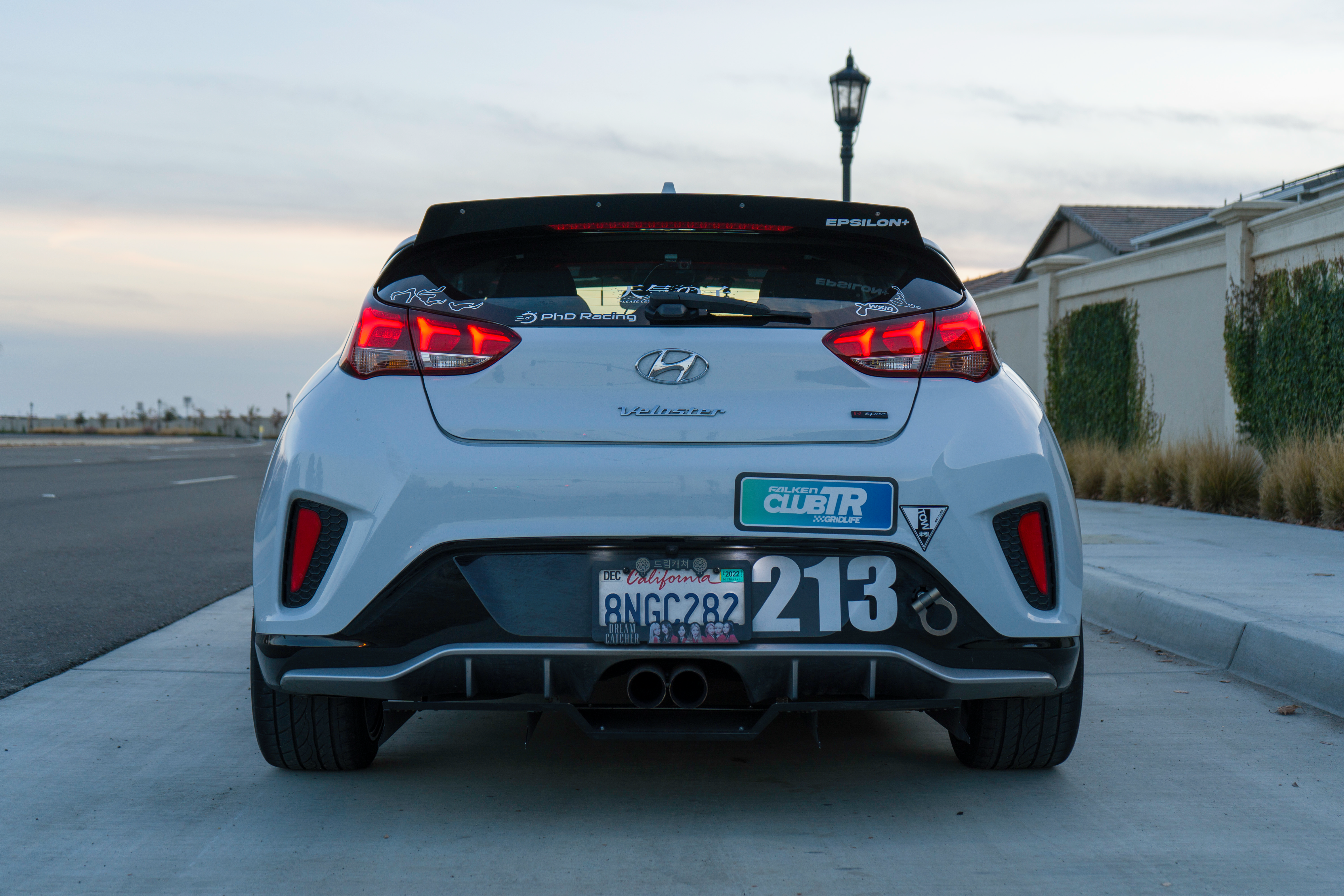 Rear view of a white Veloster R with spoiler extension parked in a driveway