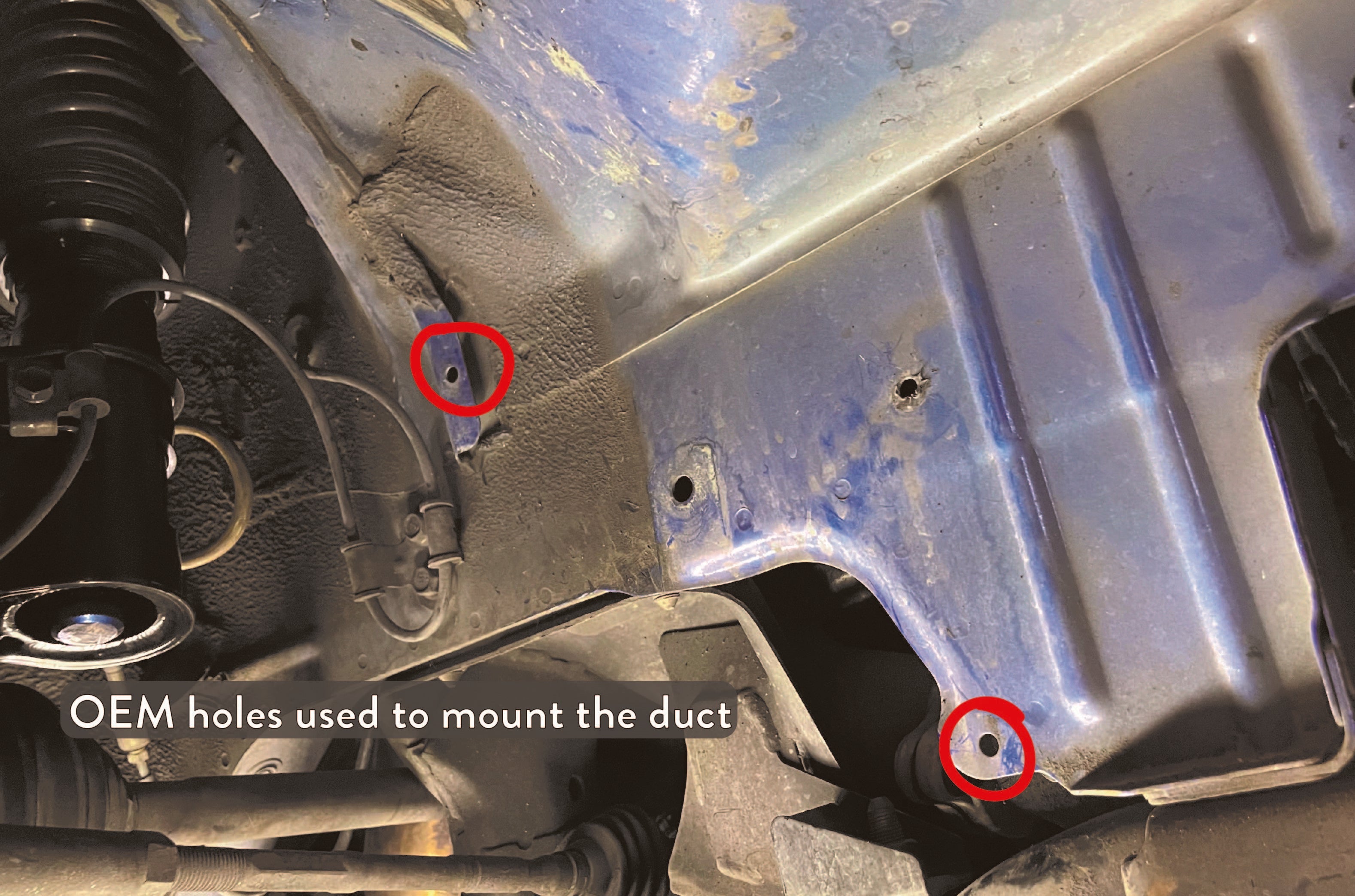 Close-up of the OEM inner fender liner holes used to mount the duct kit