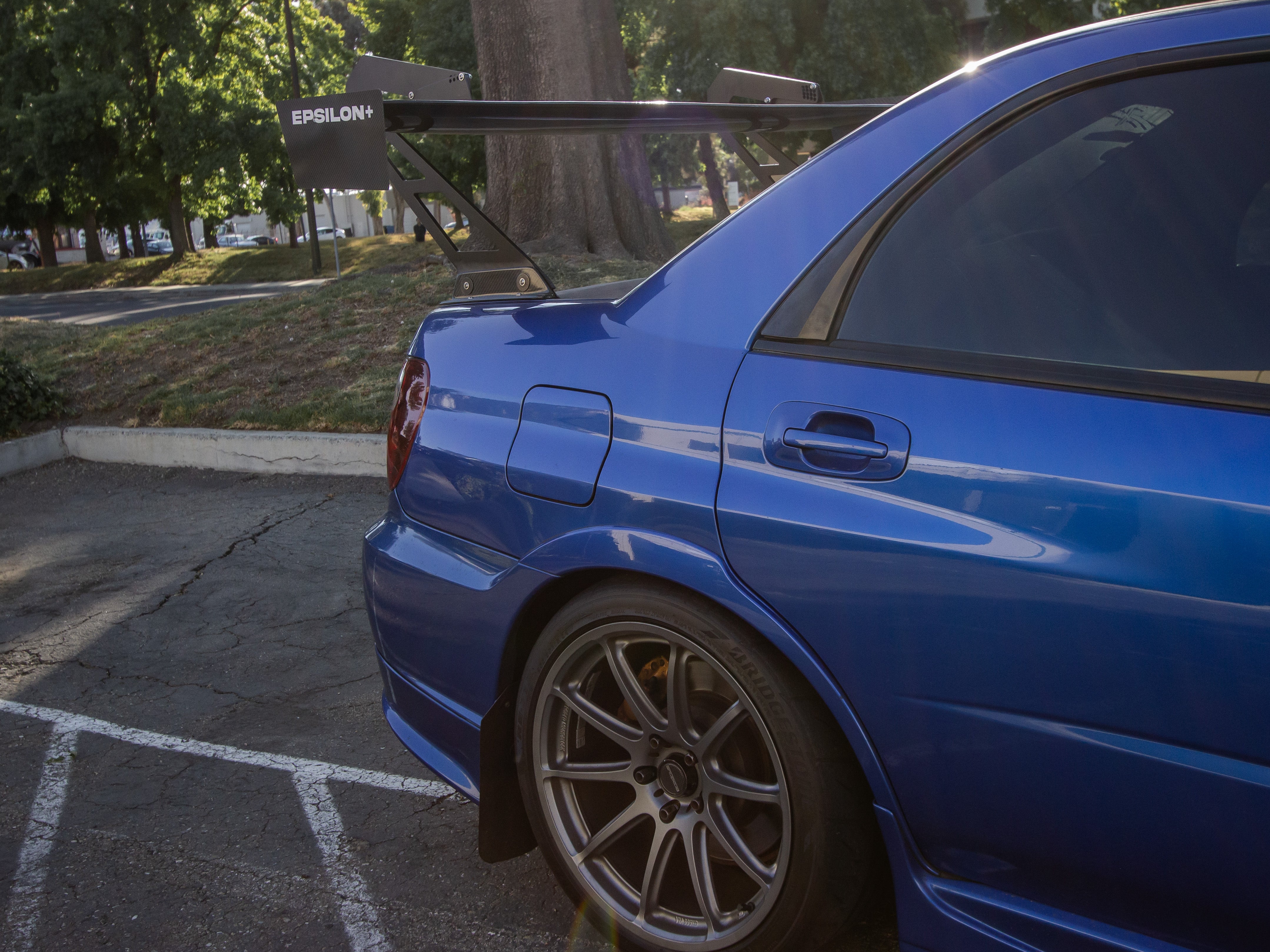 Close-up of the GT wing swan mount on a blue Impreza GD trunk