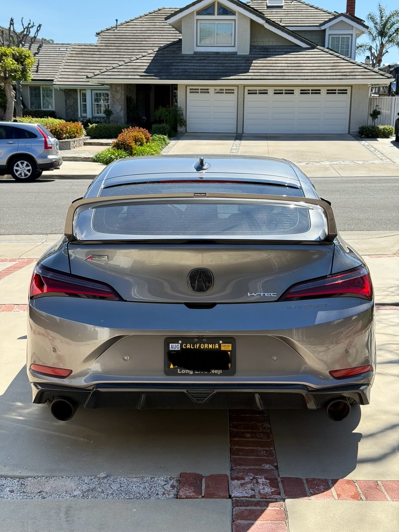 Rear view of a gray Acura Integra showing the Sport Wing and taillights