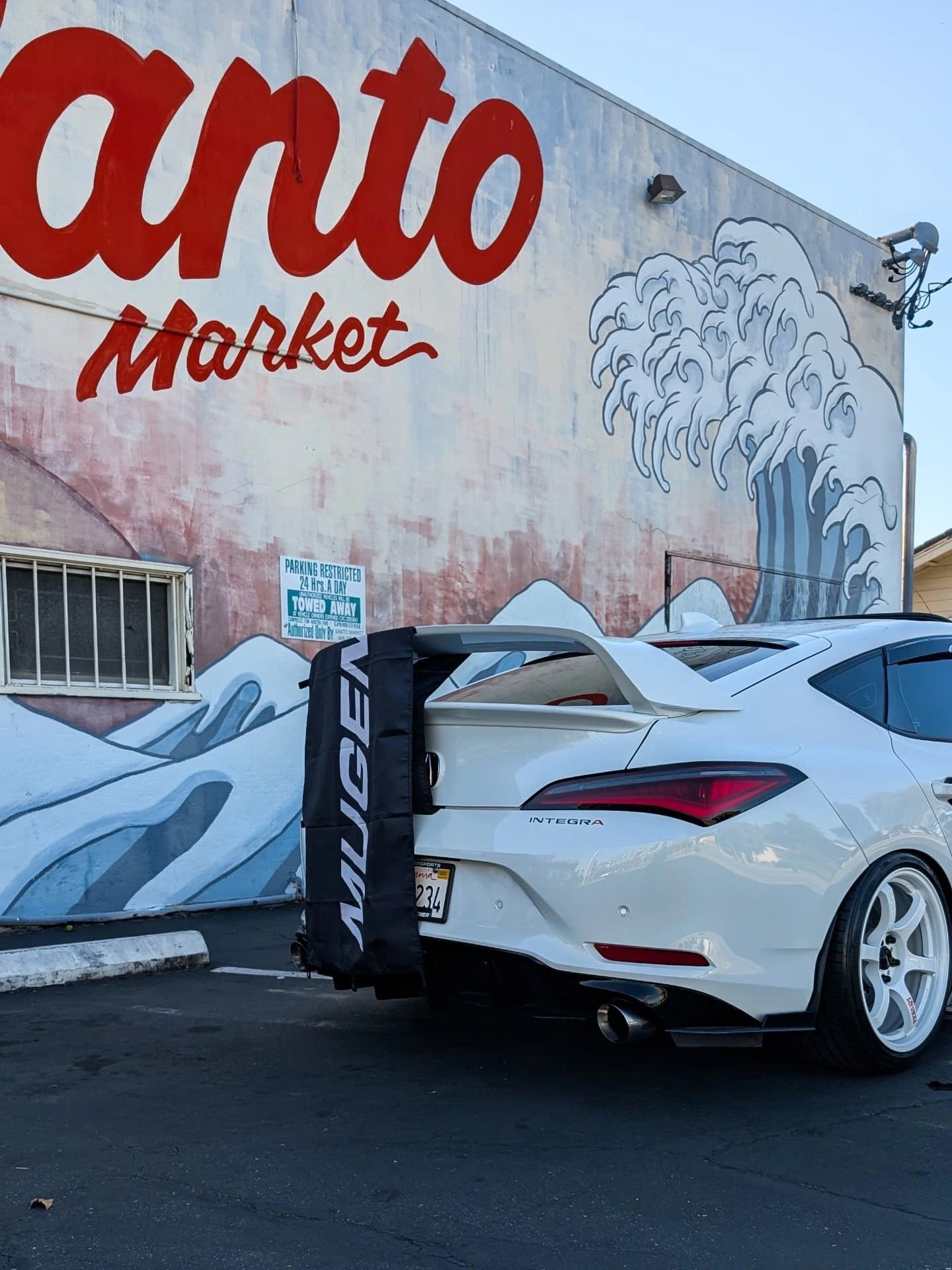White Acura Integra with Sport Wing parked beside a painted mural wall