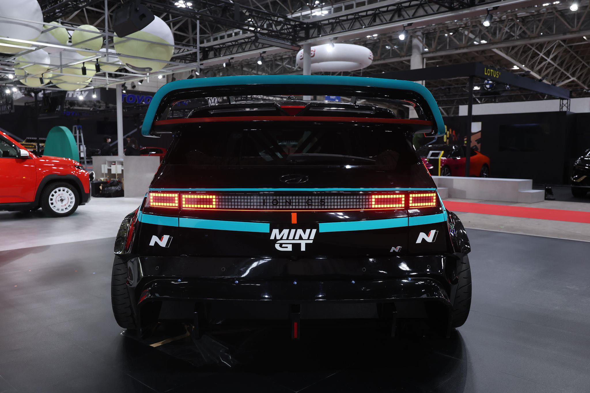 Rear view of a Hyundai Ioniq 5N fitted with the Epsilon+ R1 carbon wing on display at an indoor auto show
