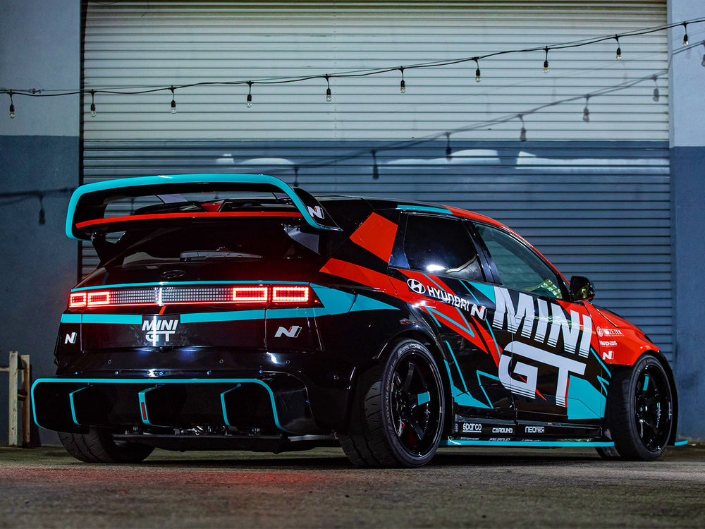 Black Hyundai Ioniq 5N with Epsilon+ R1 double-decker carbon wing, rear three-quarter view outside a garage