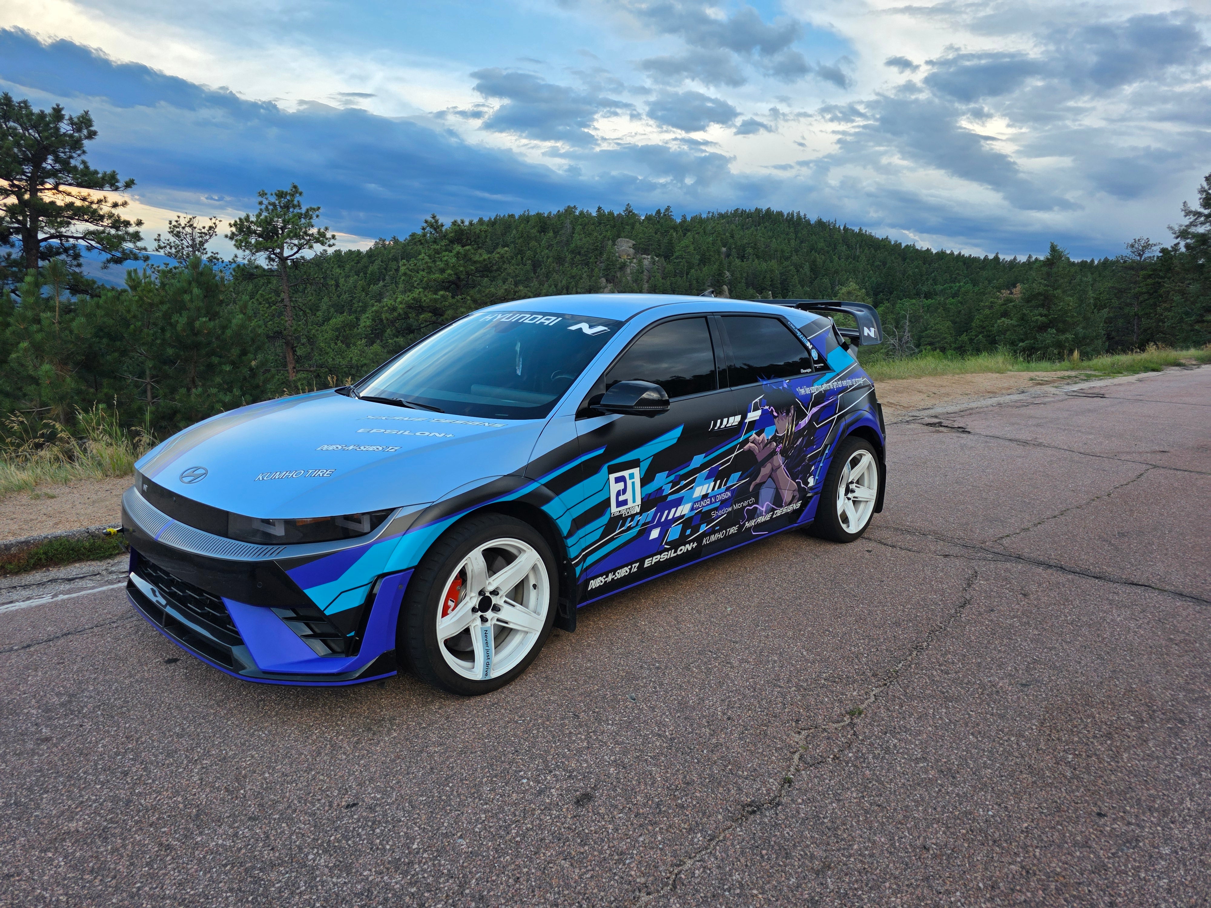 Front three-quarter view of a blue Hyundai Ioniq 5N equipped with the Epsilon+ R1 carbon rear wing