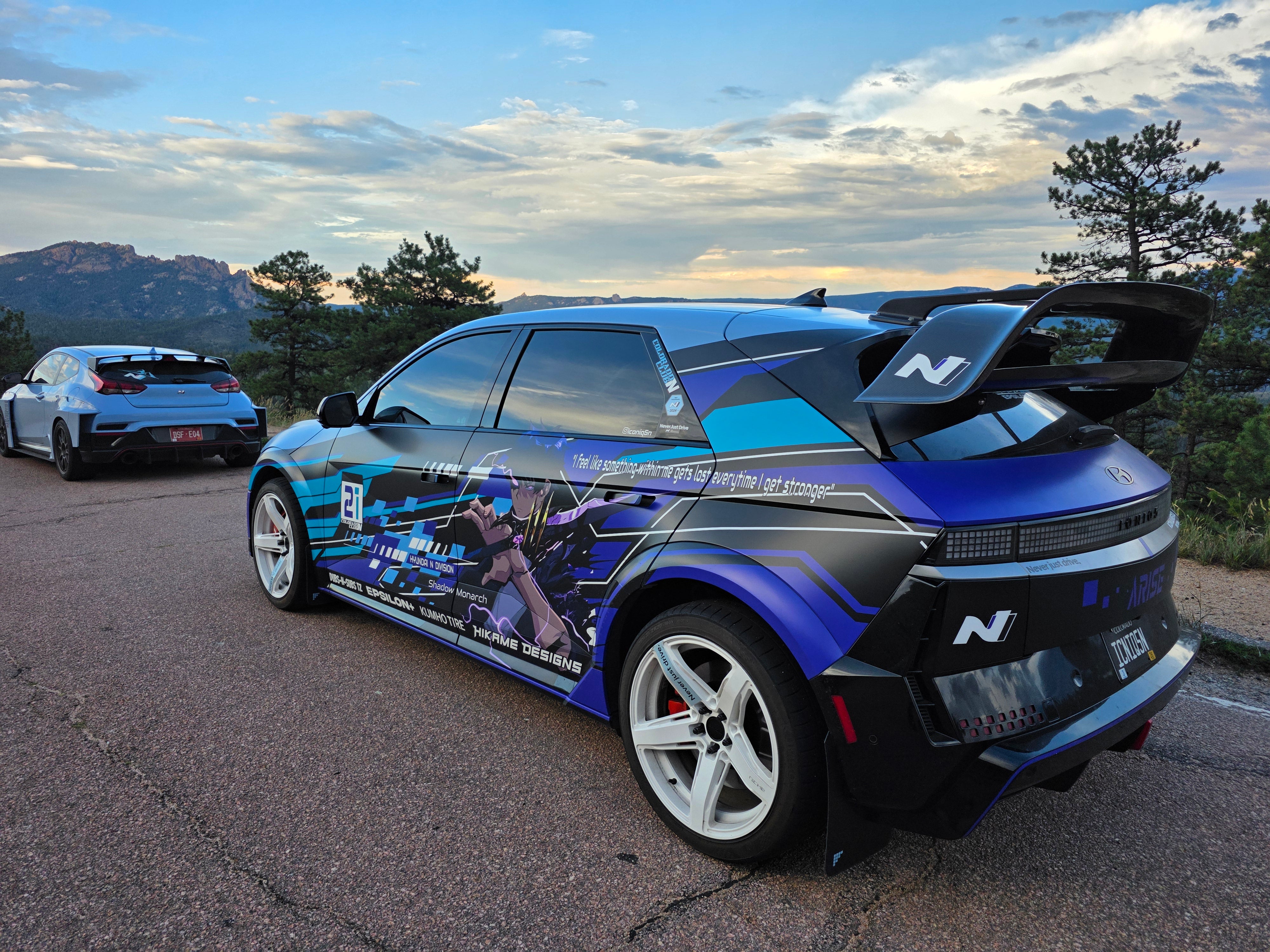 Blue liveried Hyundai Ioniq 5N running the Epsilon+ R1 rally wing at a mountain overlook at dusk