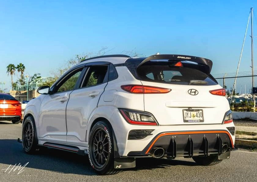Rear three-quarter view of a white Kona N with spoiler extension parked outdoors
