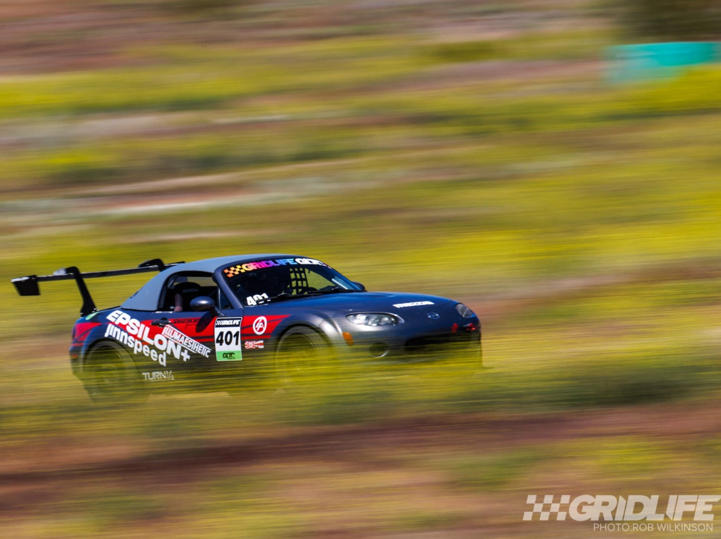 Mazda MX-5 Miata NC motorsport car with GT wing, panning shot on track