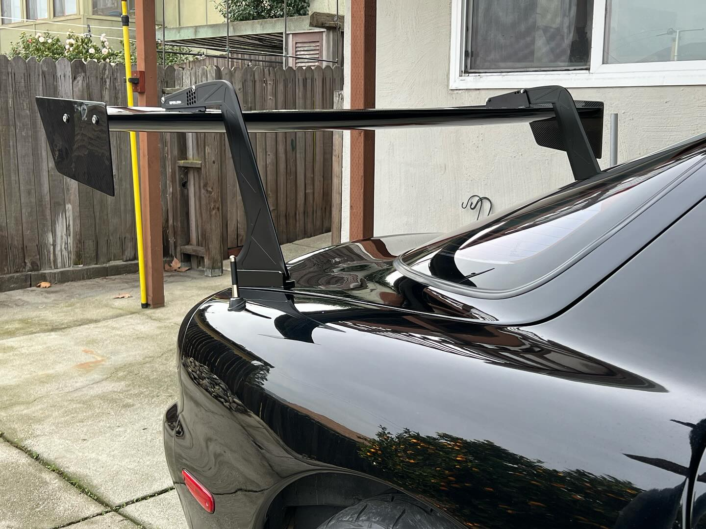 Rear view of the GT wing mounted on a black Mazda RX-7 trunk