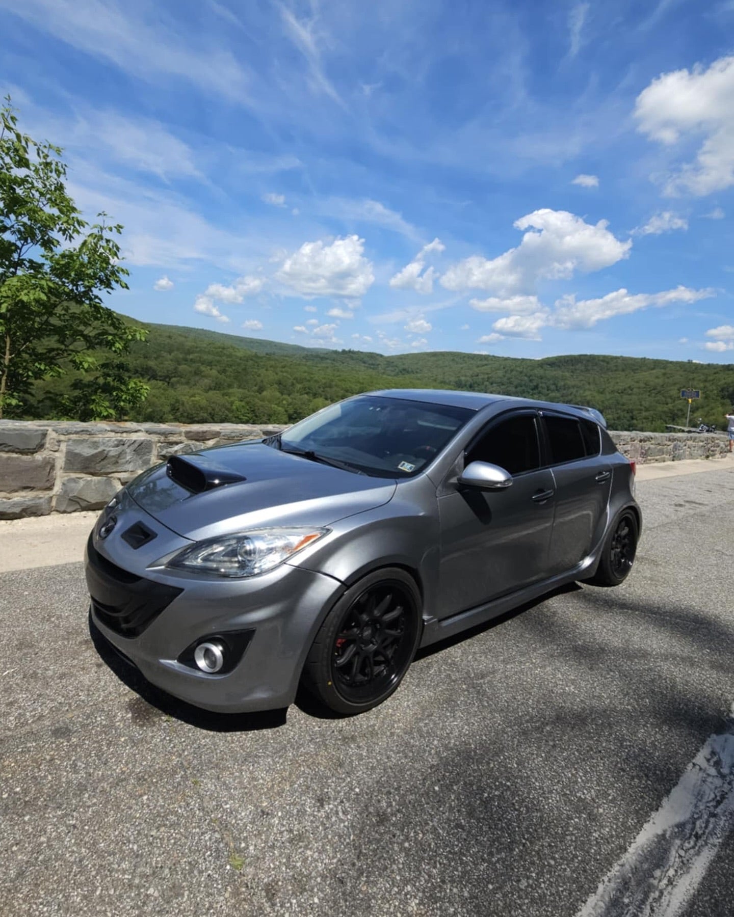 Grey Mazdaspeed3 BL with widebody fender flares parked on a scenic road