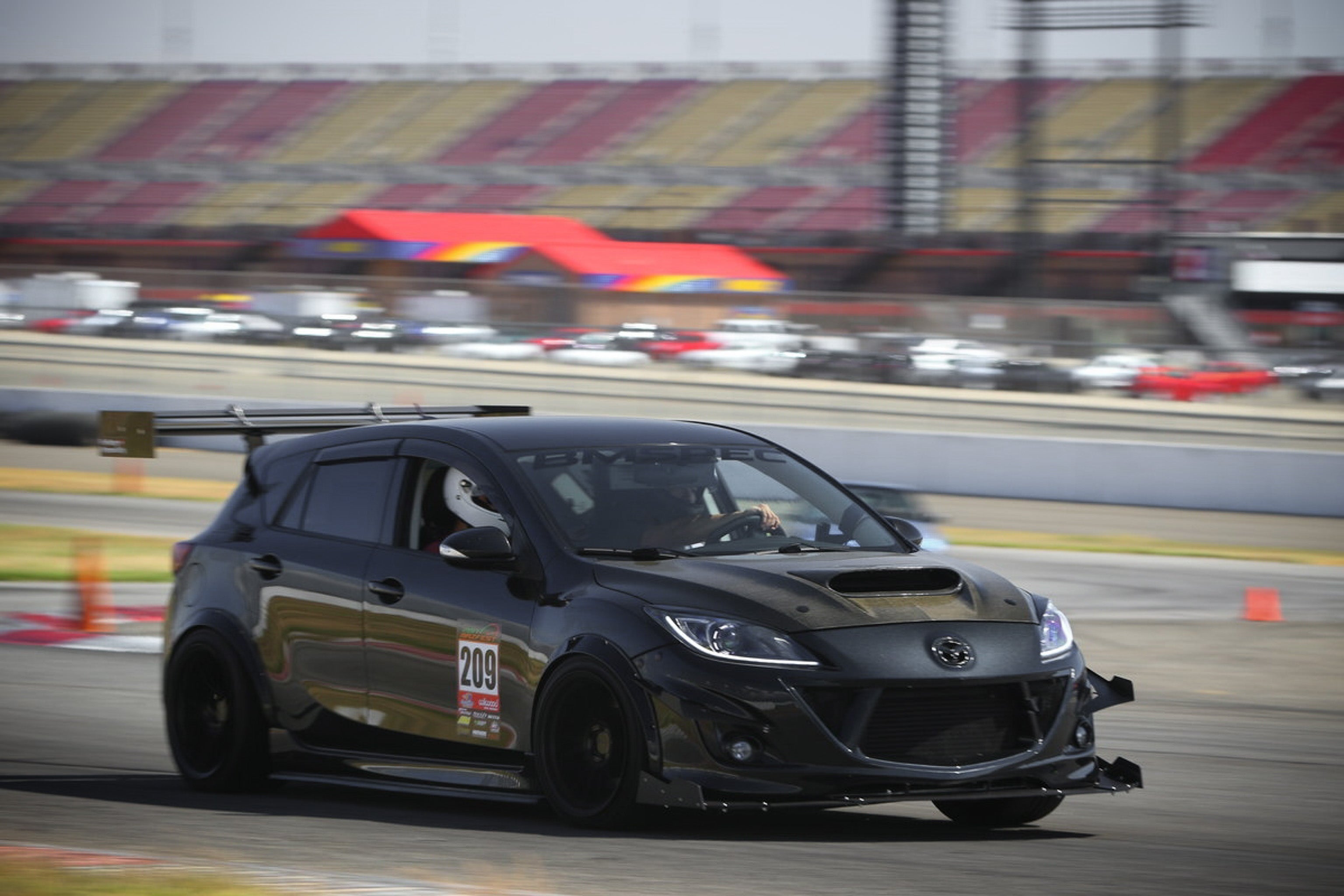 Black Mazdaspeed3 Gen2 race car with front splitter cornering hard on track