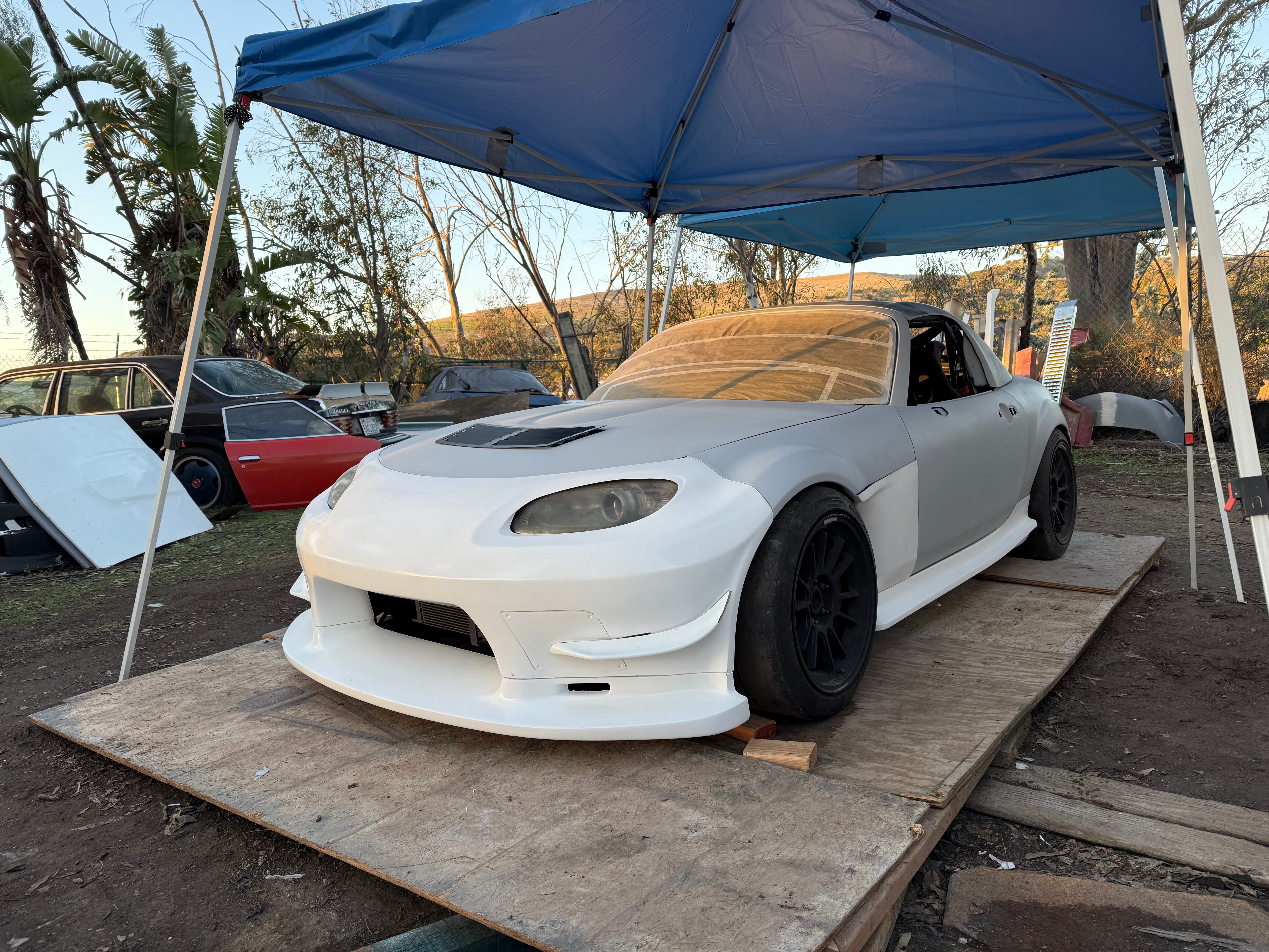 White Mazda MX-5 Miata NC with the unpainted Epsilon+ aero kit, front three-quarter view