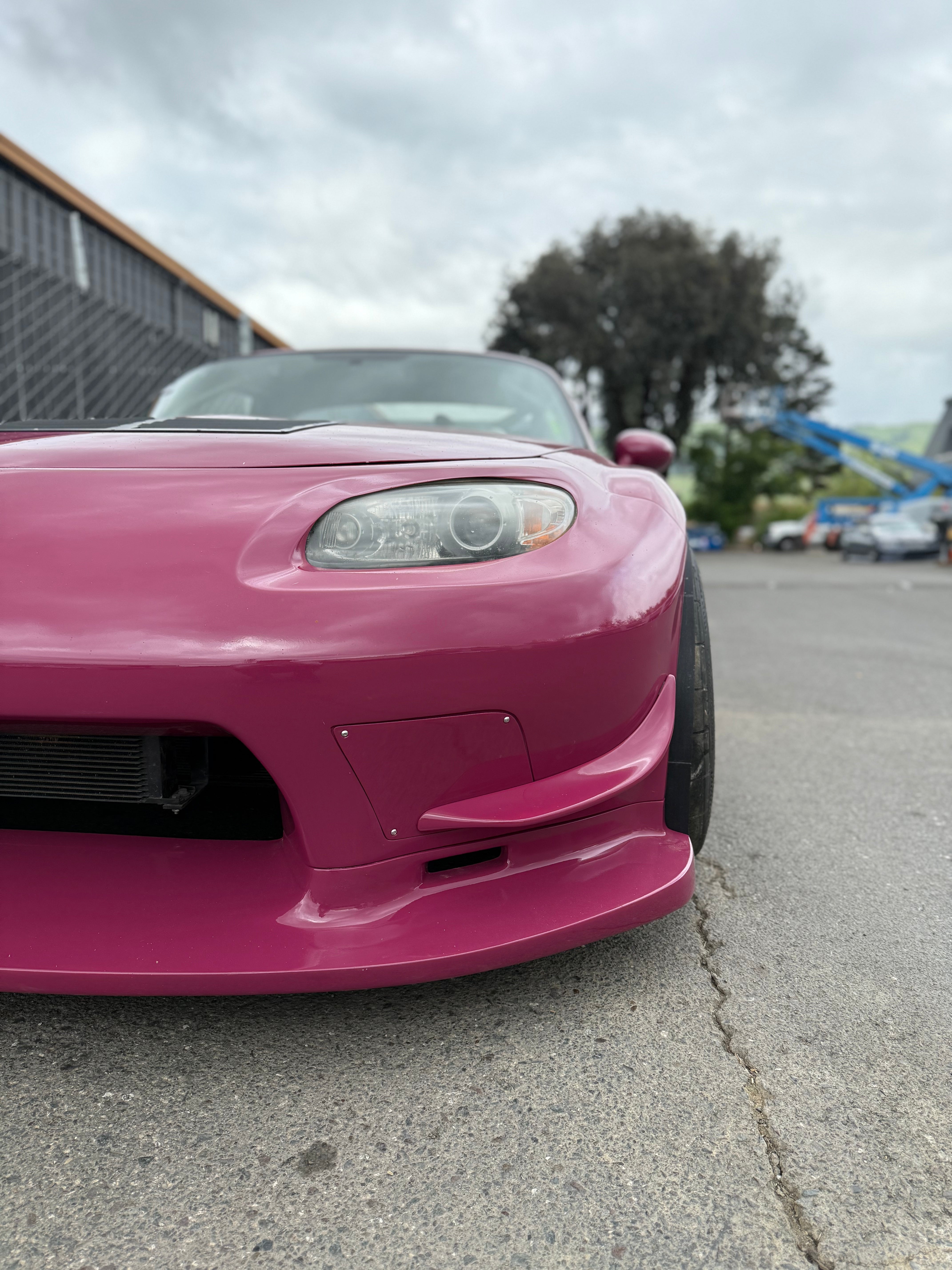Close-up of a canard on the front bumper corner of a pink Miata NC