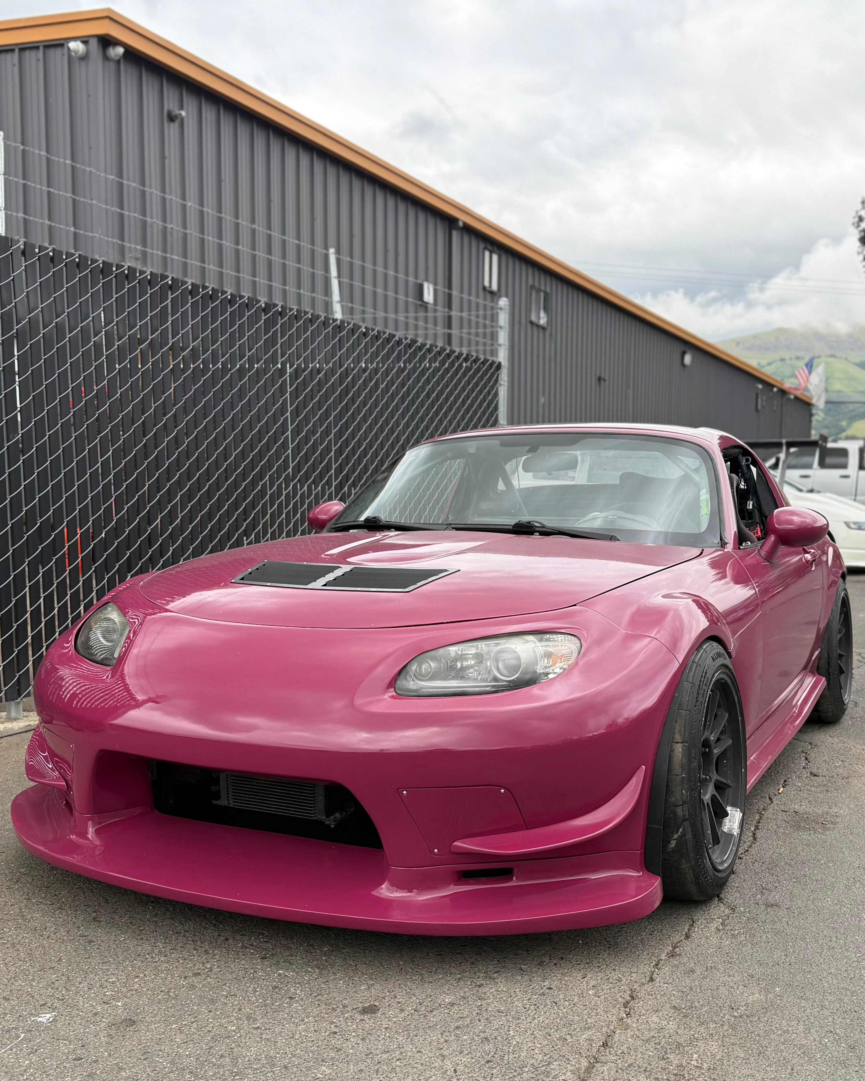 Pink Mazda MX-5 Miata NC with canards and vented hood, front three-quarter view