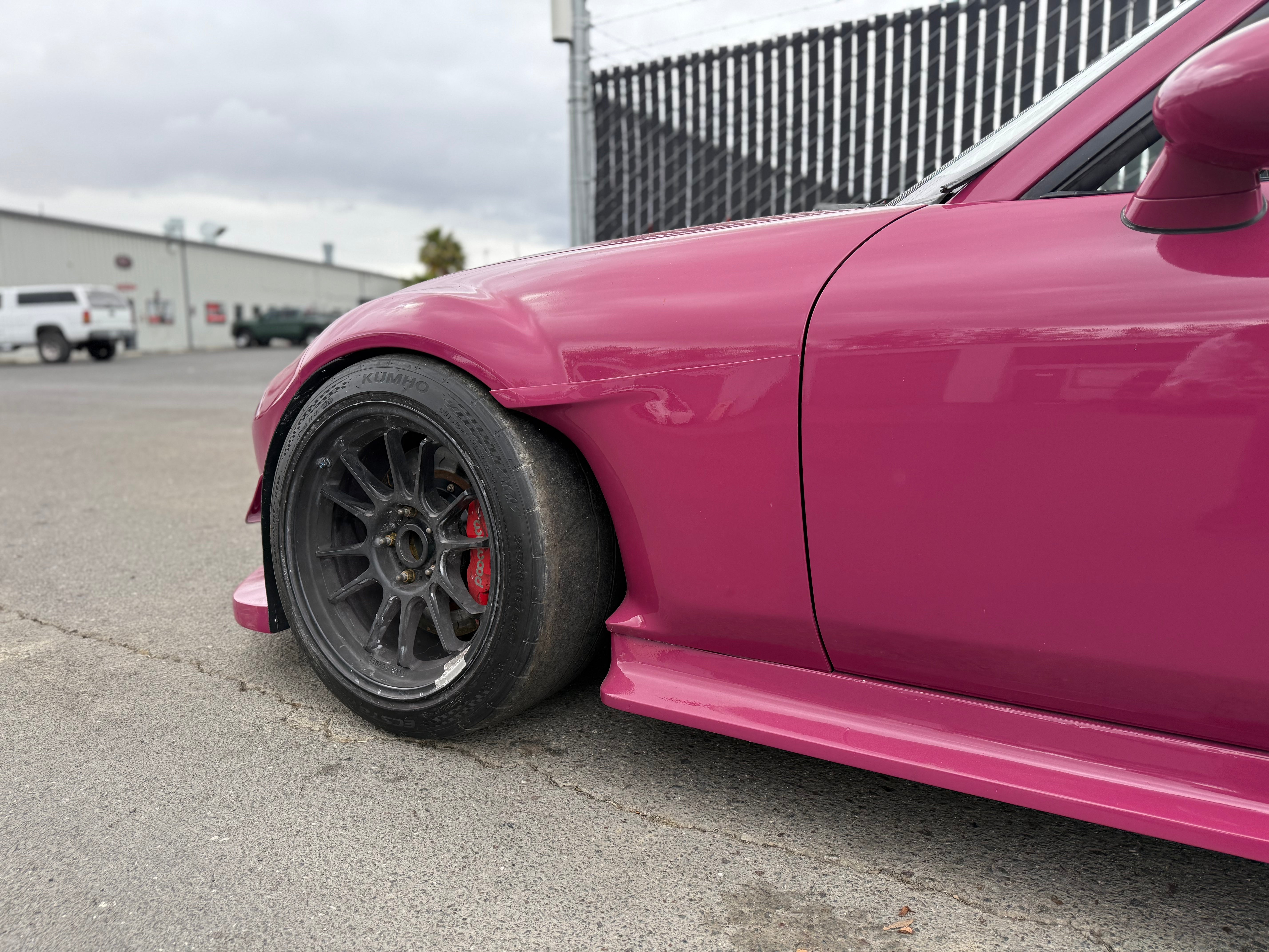 Close-up of the front fender cut and wheel on a pink Mazda MX-5 Miata NC