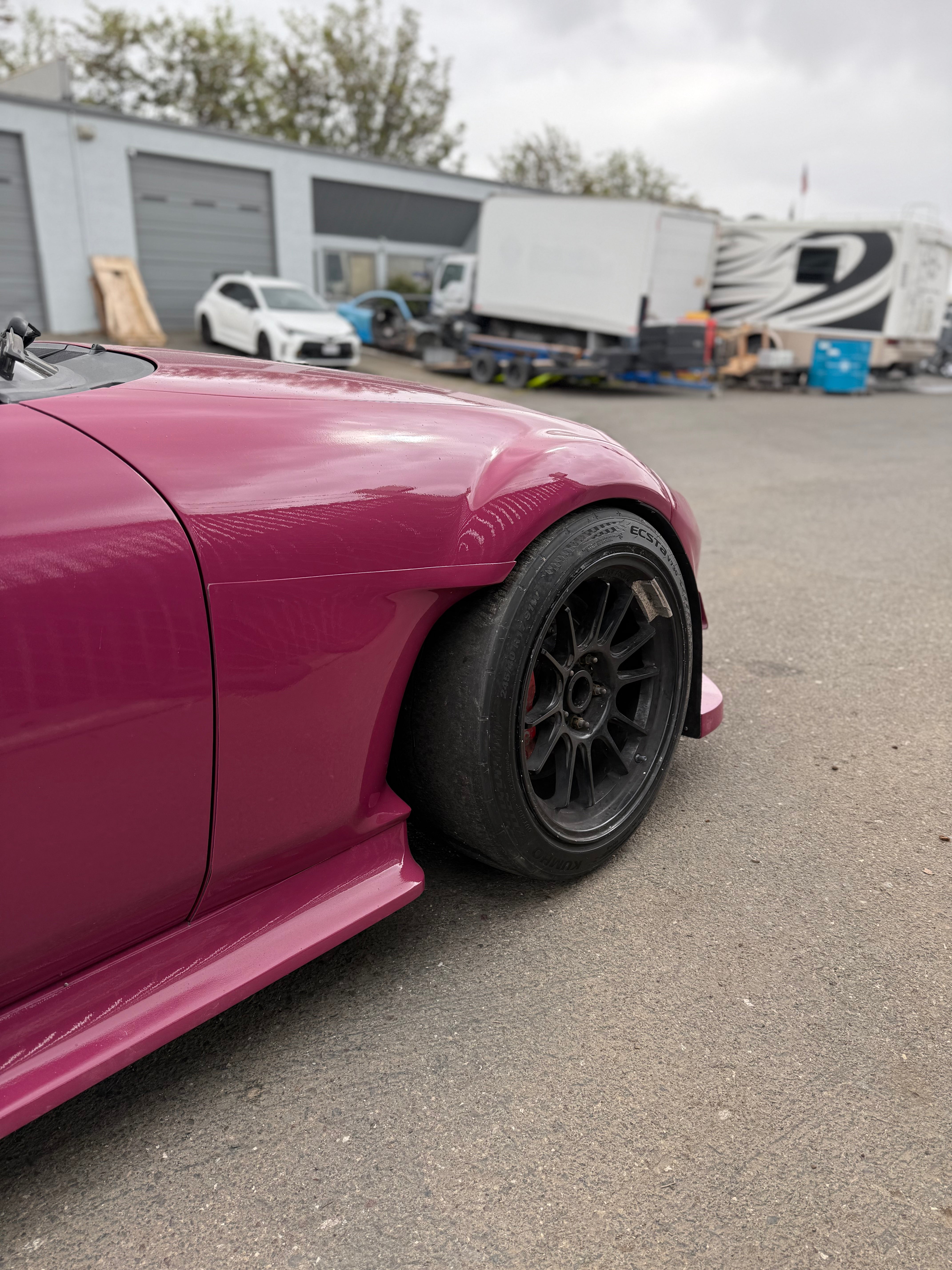 Close-up of the rear fender cut behind the wheel on a pink Miata NC