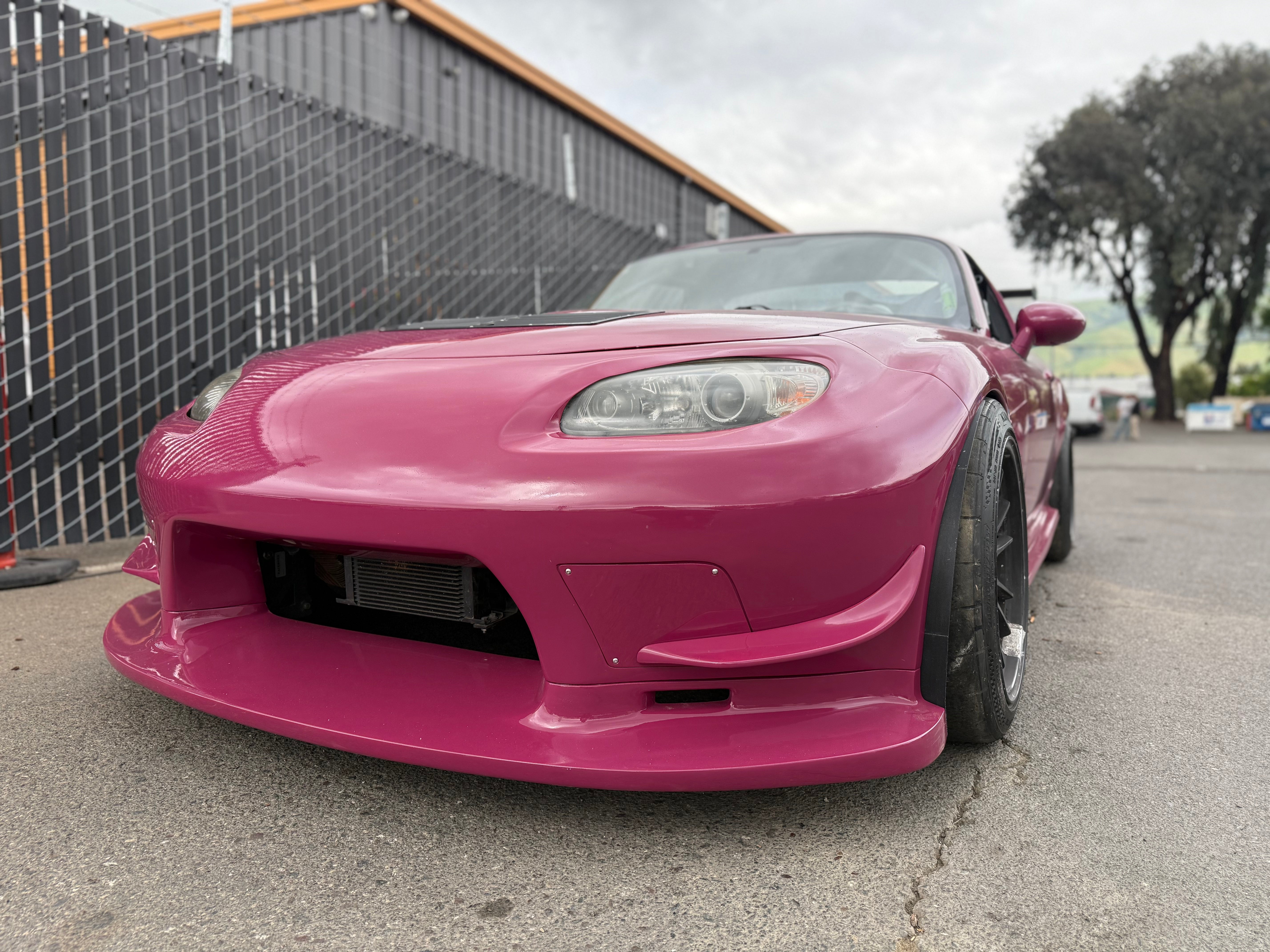 Elevated front three-quarter view of a pink Mazda MX-5 Miata NC with front bumper